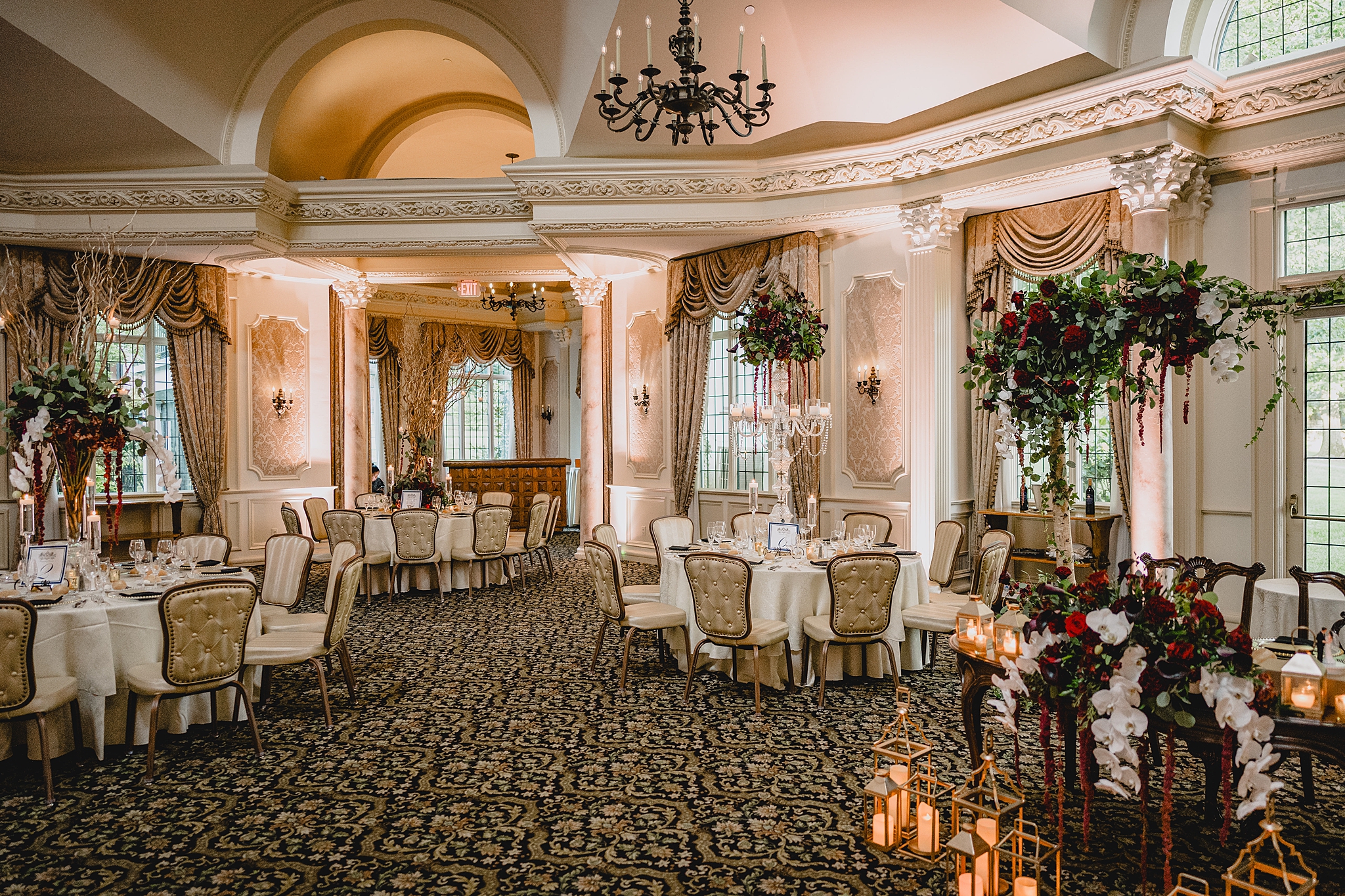 wedding reception in ballroom at Pleasantdale Chateau with red and white flowers and candles throughout the room