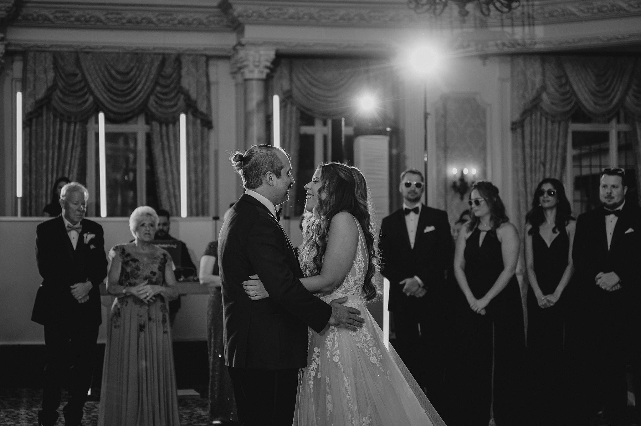 newlyweds grin inside ballroom during first dance room at Pleasantdale Chateau