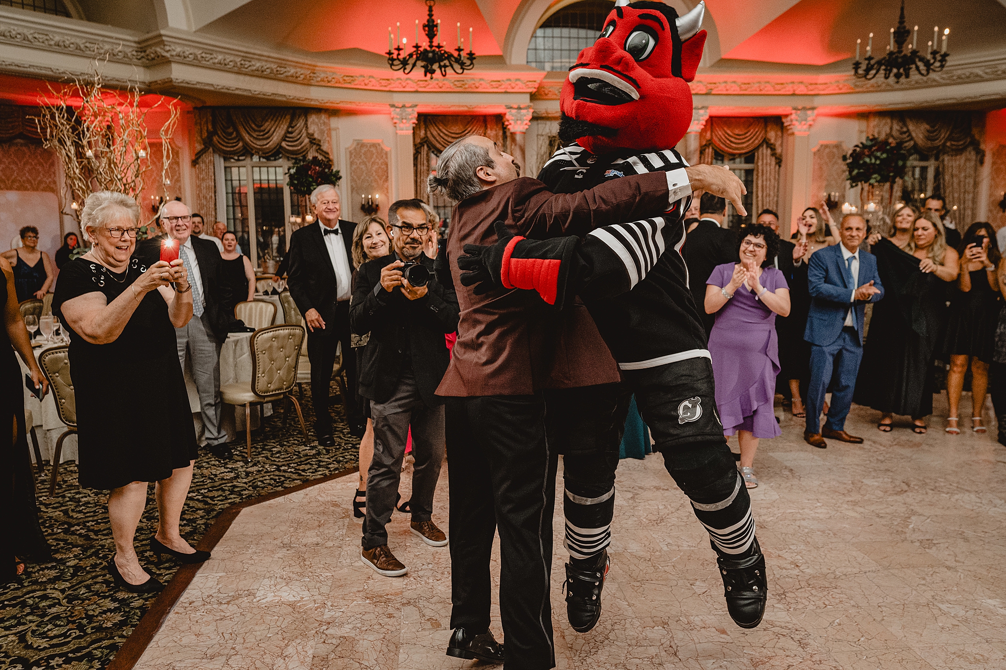 groom hugs Red Devil mascot in ballroom at Pleasantdale Chateau