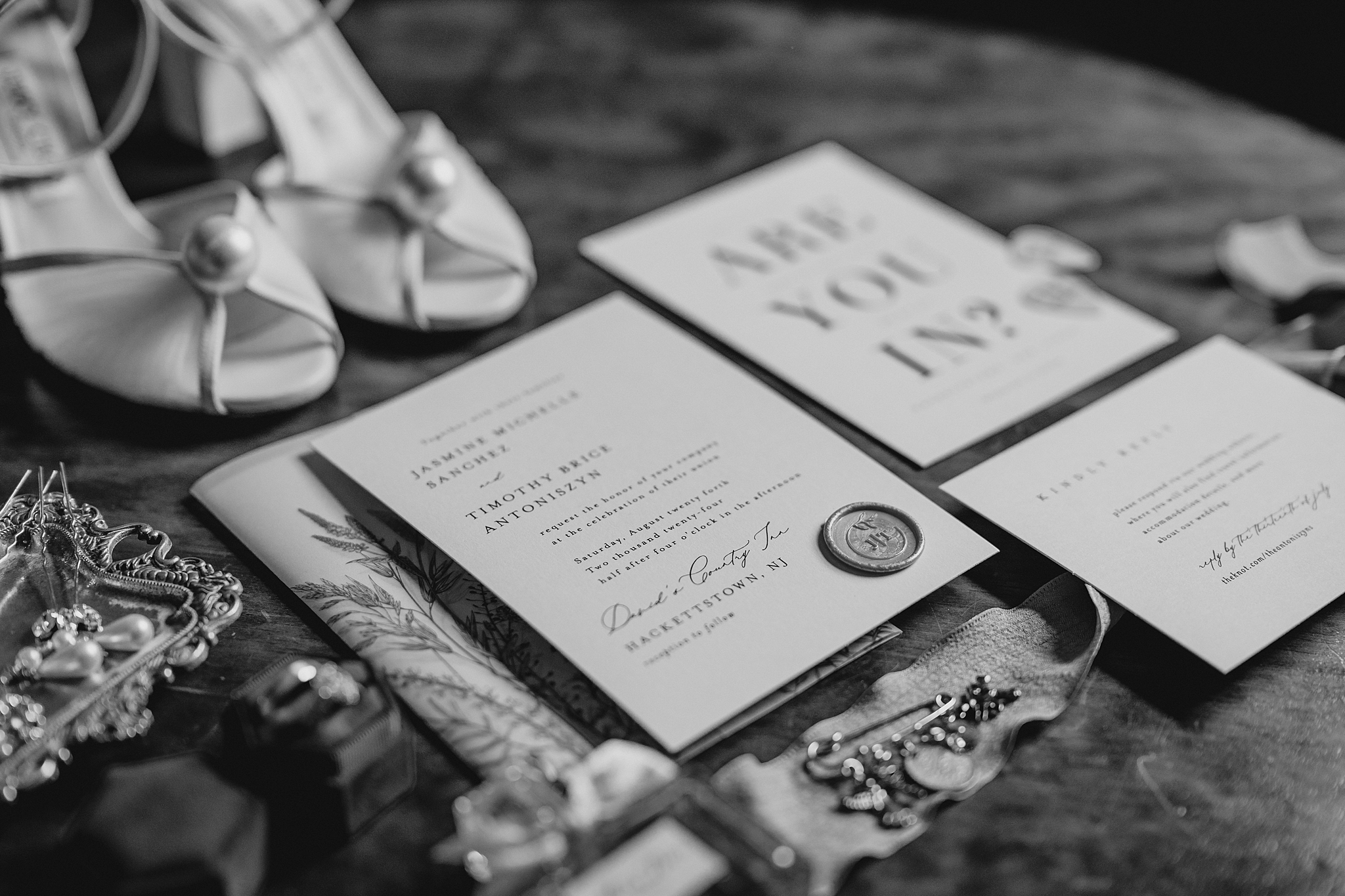 invitation suite with wax seal and vellum cover sits in front of bride's shoes