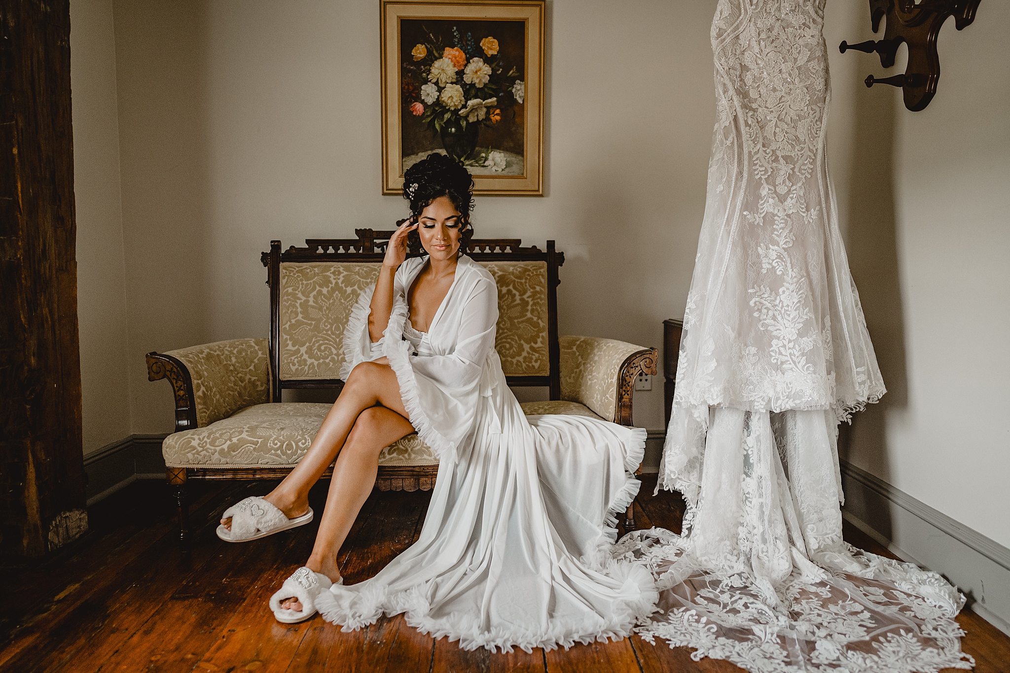 bride sits in robe with scrunched tulle on the hem on couch inside David's Country Inn