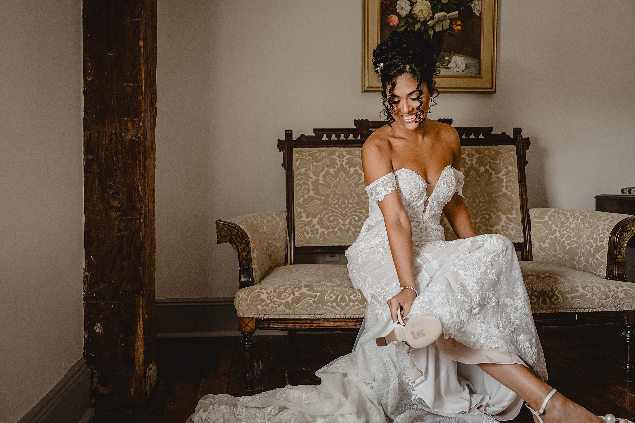 bride sits on couch putting on shoes inside suite at David's Country Inn