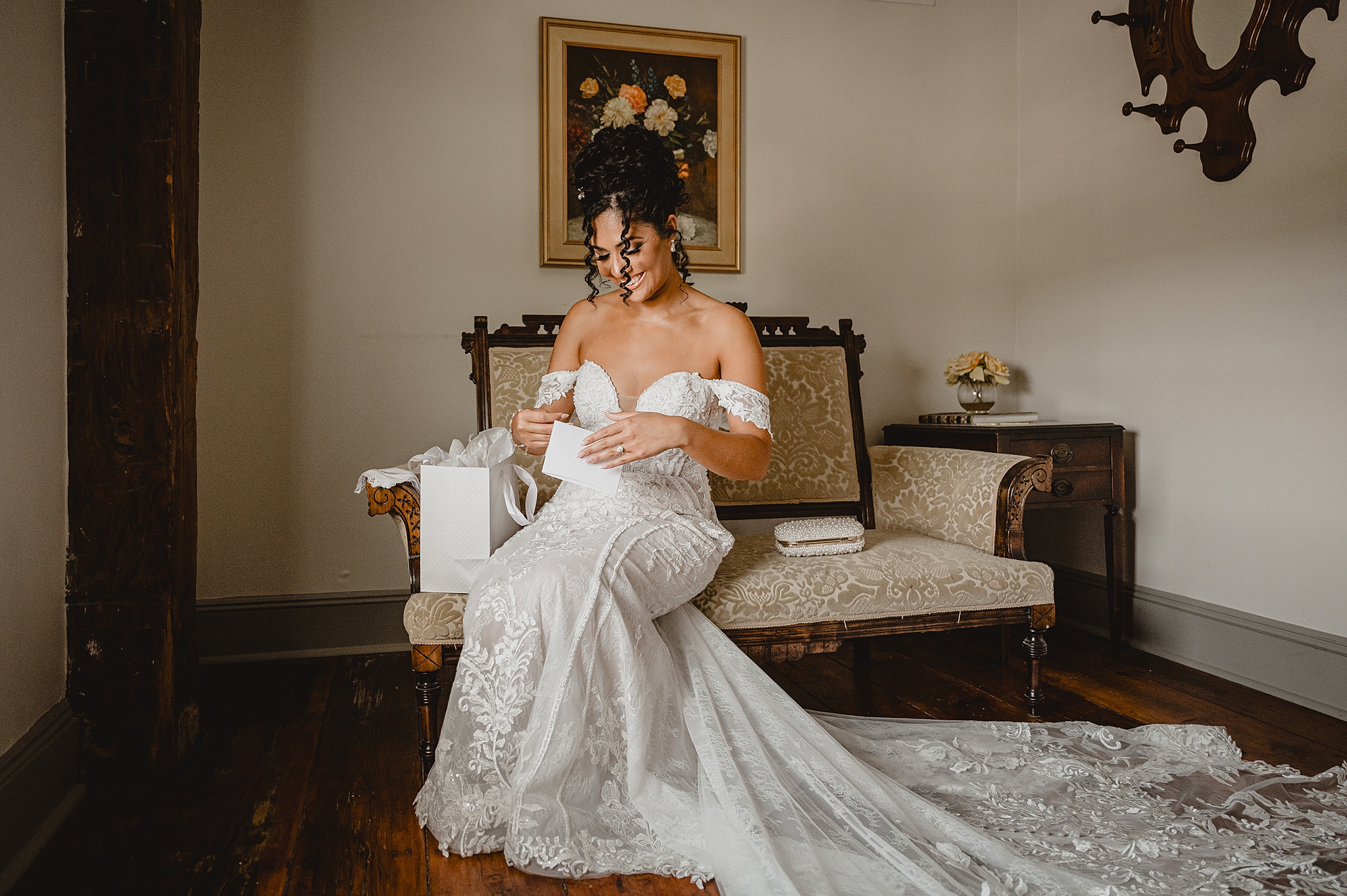 bride sits on couch looking at gift and card from groom