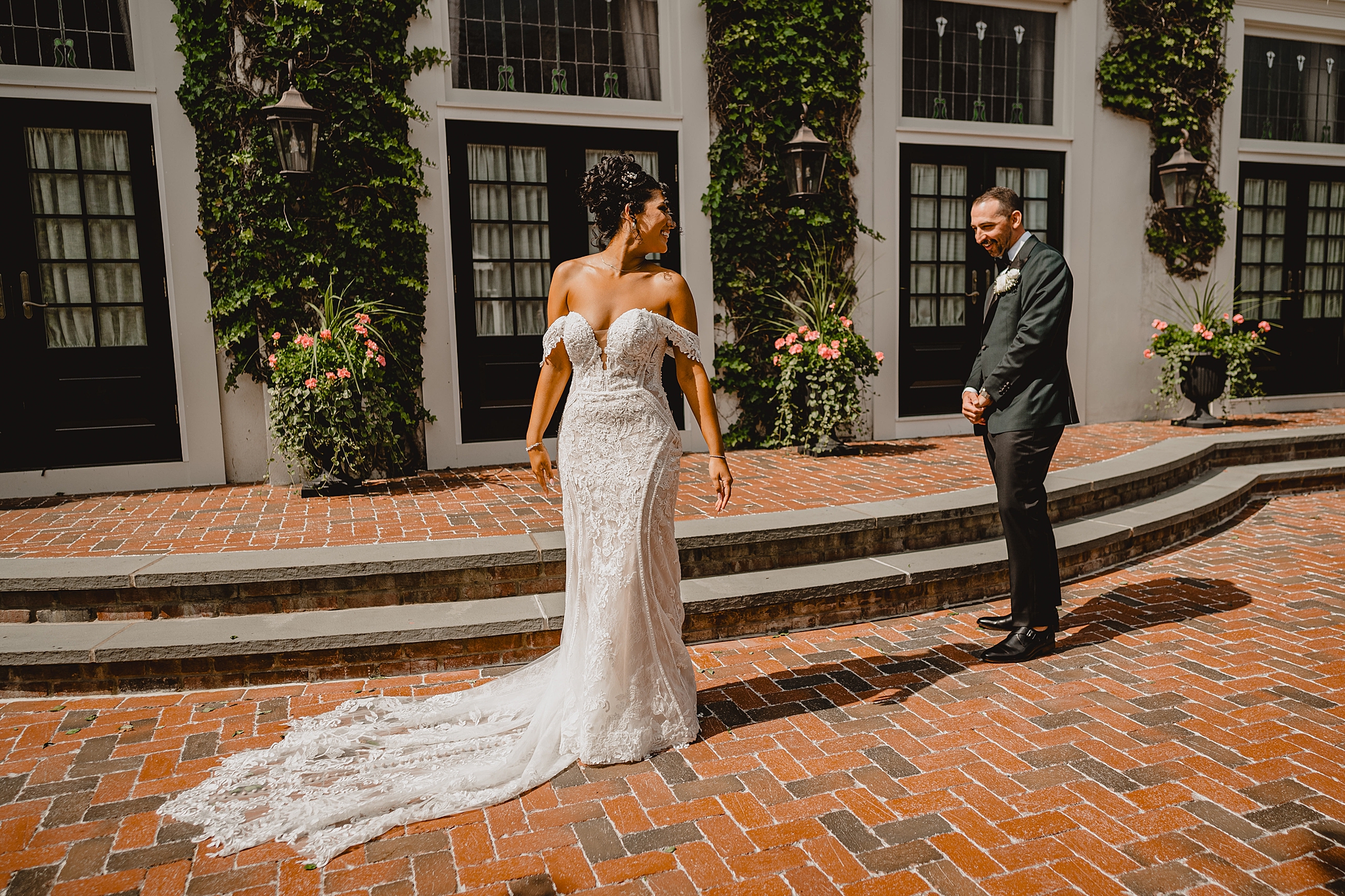 bride shows off back of wedding dress to groom during first look on patio at David's Country Inn