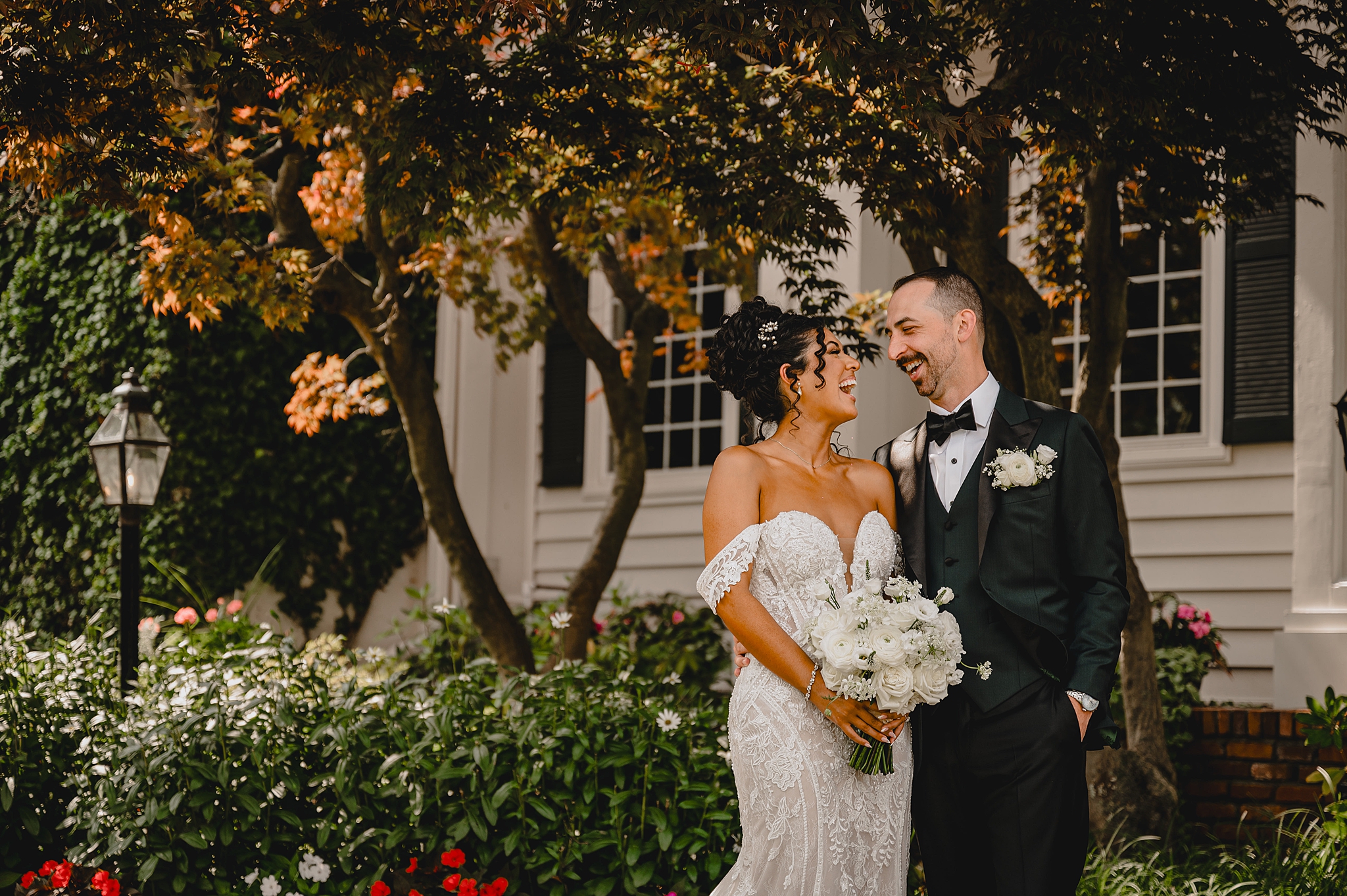 newlyweds laugh standing together under trees in New Jersey