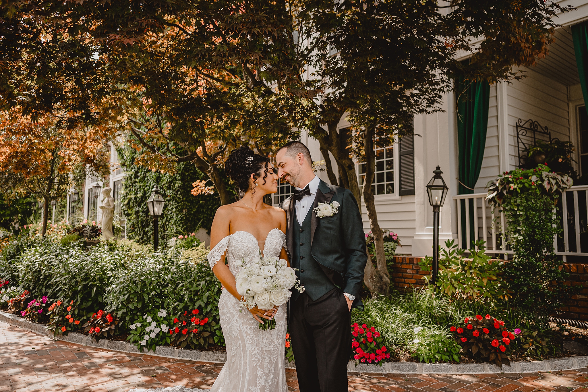 bride and groom smile leaning heads together on patio with flowers overflowing around them