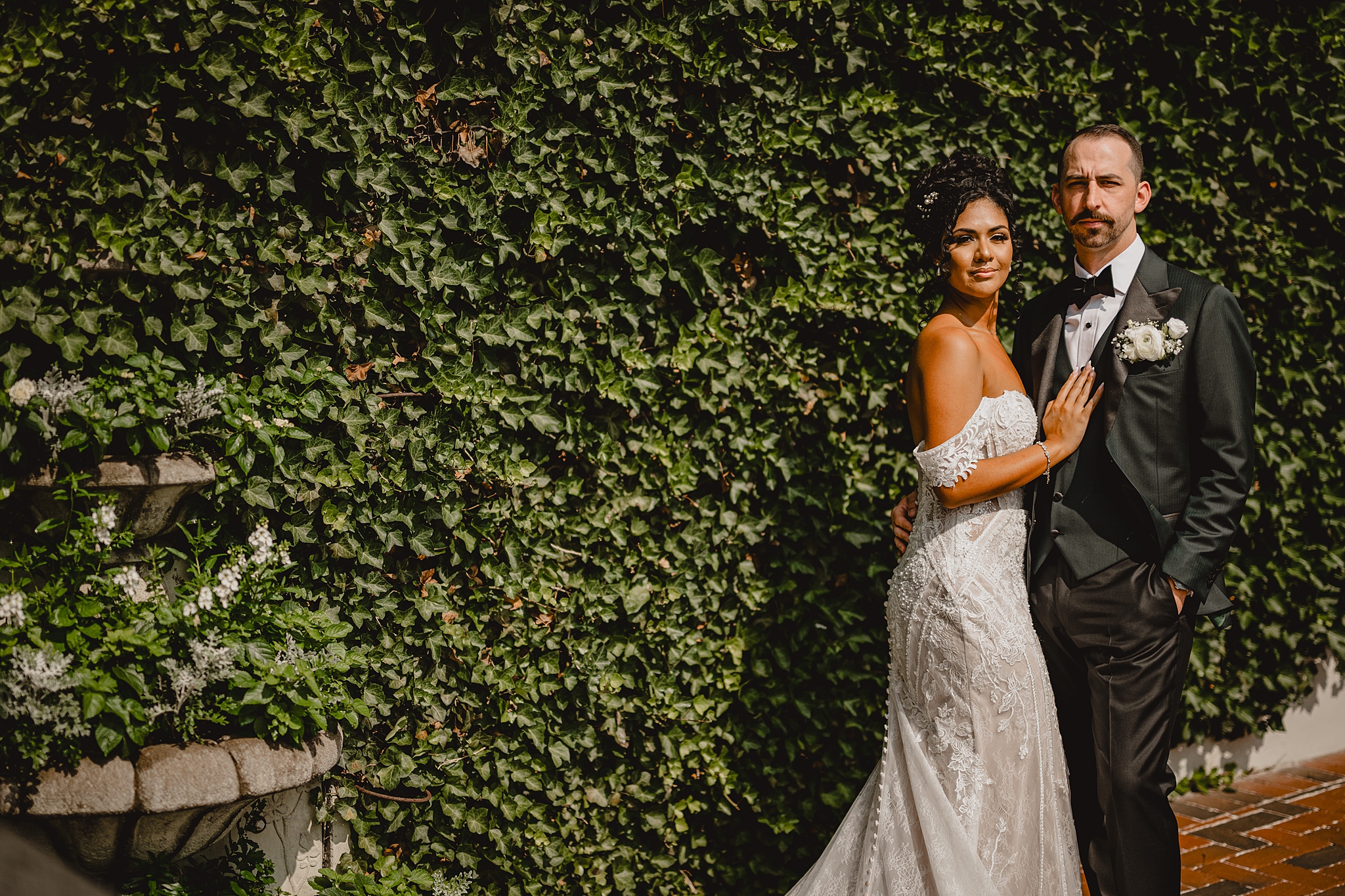 bride rests hands on groom's chest in front ivy covered wall in NJ venue 