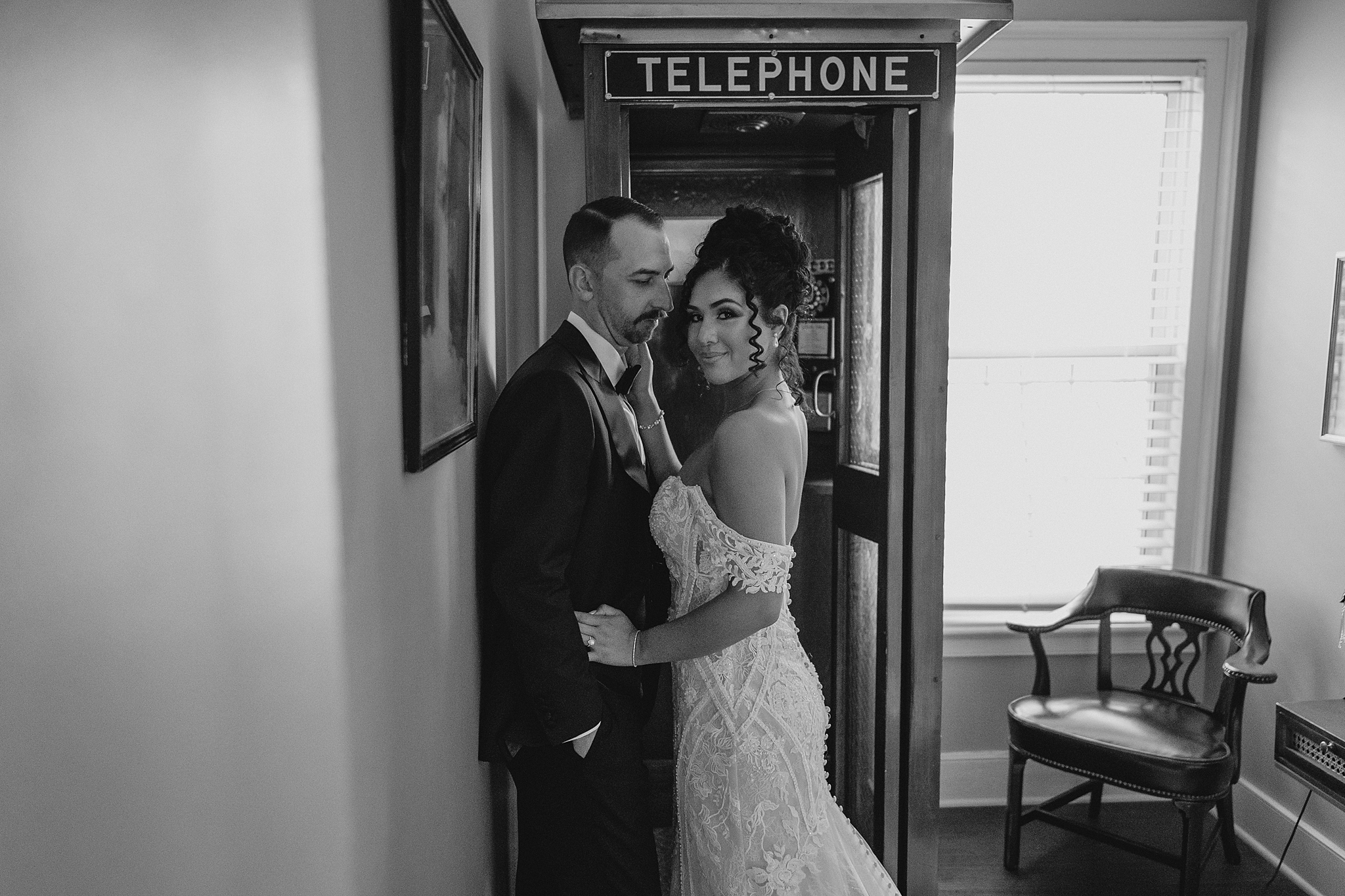 newlyweds lean against the wall in front of vintage telephone booth inside David's Country Inn
