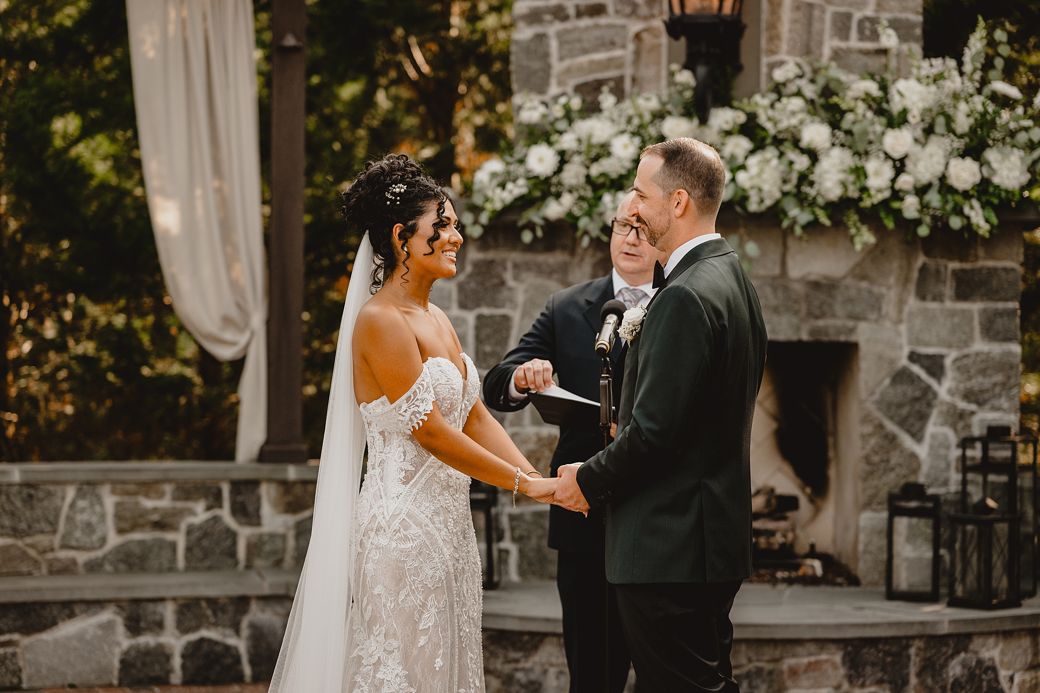 newlyweds hold hands during vows on stone patio at David's Country Inn