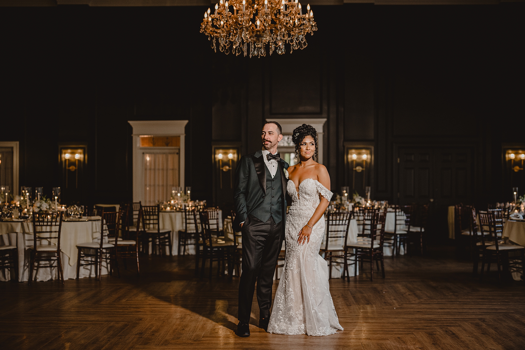 bride and groom stand together under chandelier in ballroom at David's Country Inn
