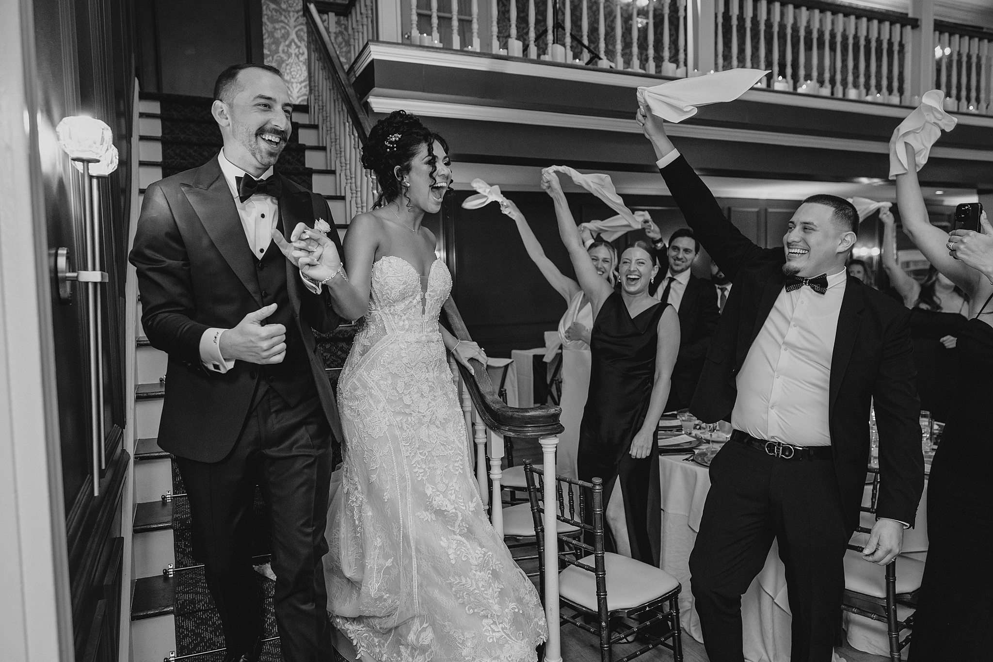 wedding guests twirls napkins as newlyweds enter ballroom for wedding reception 