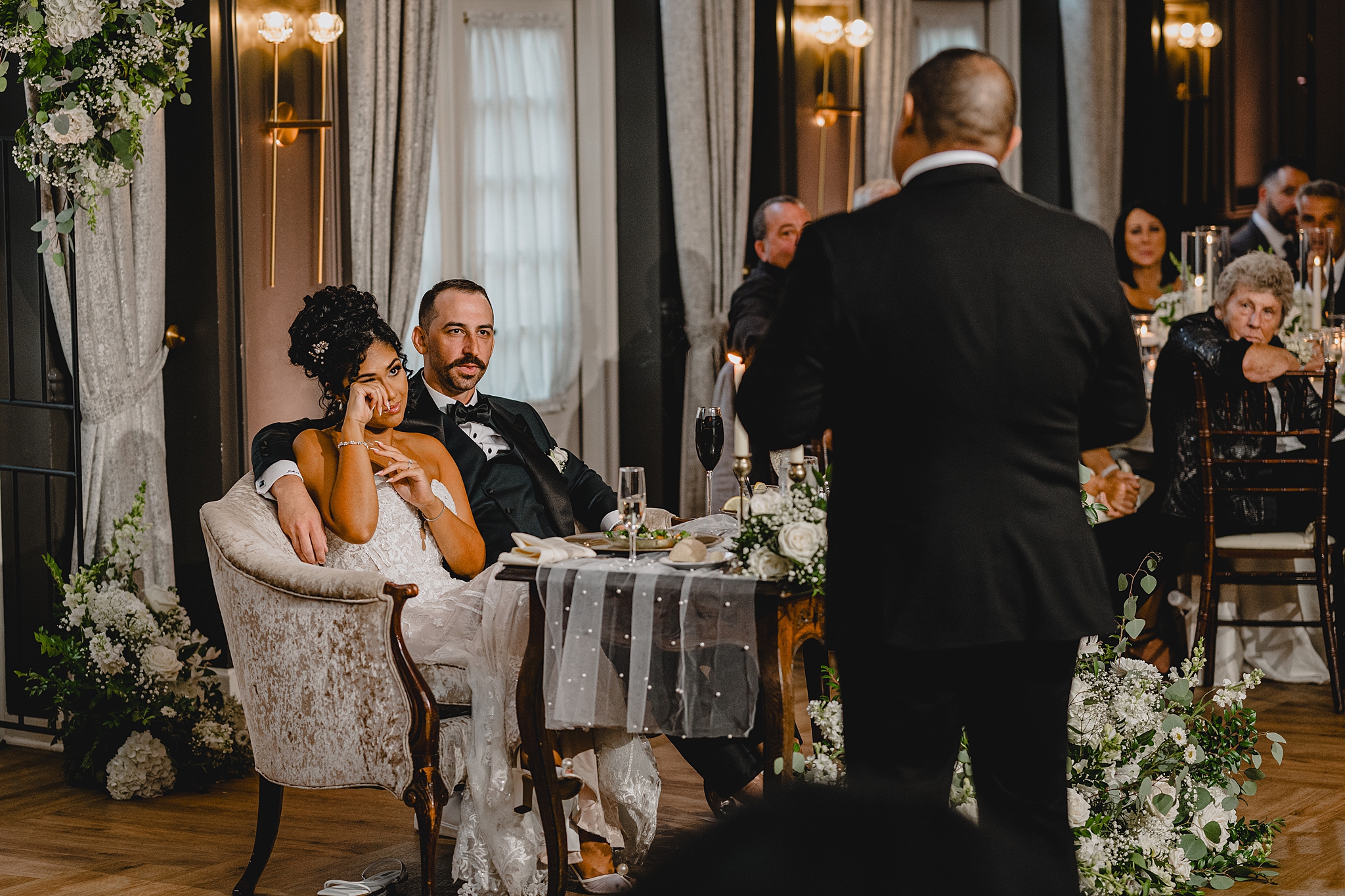 bride cries listening to speech from father sitting on sofa with groom