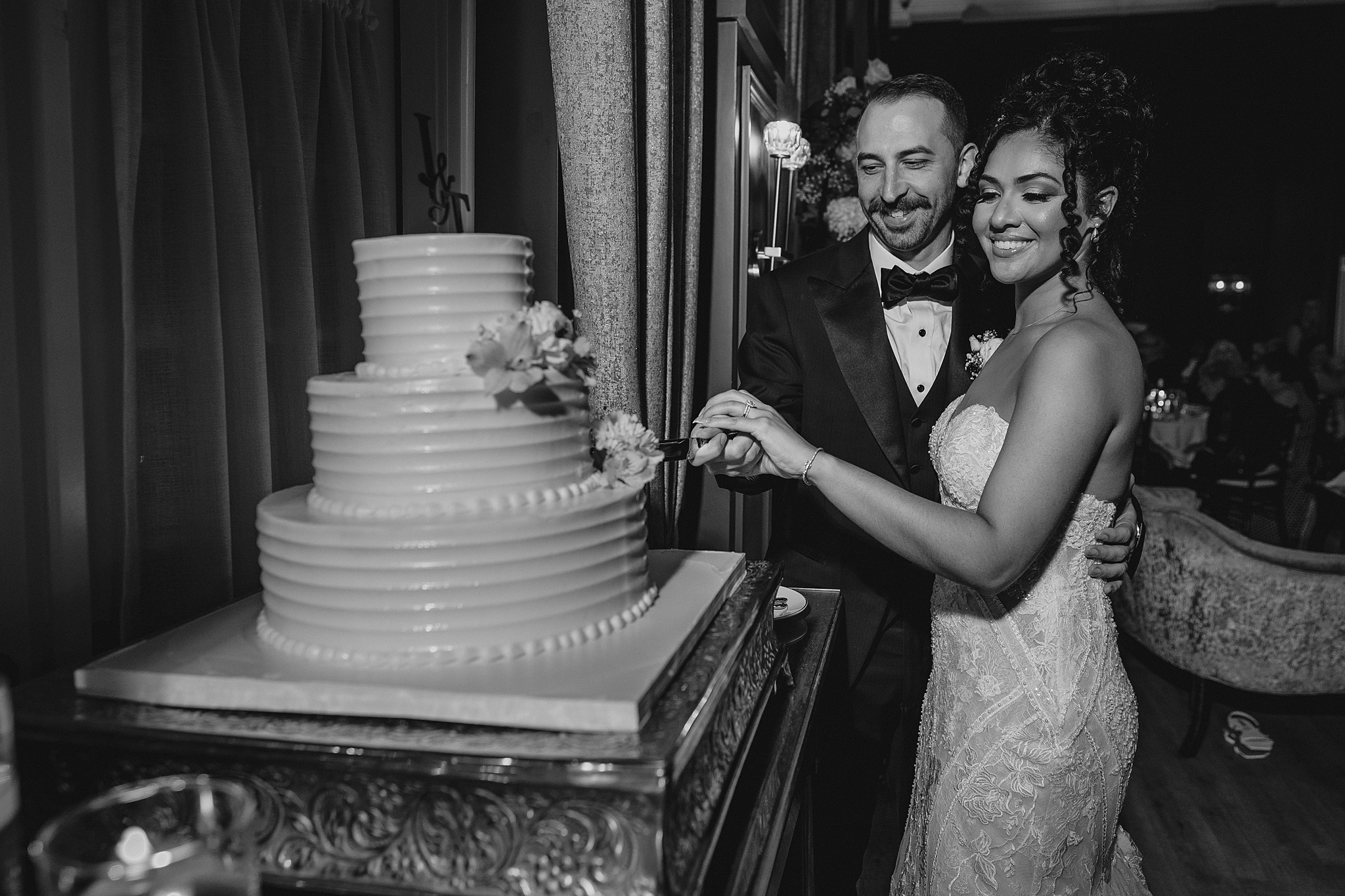 bride and groom cut tiered wedding cake decorated in traditional style
