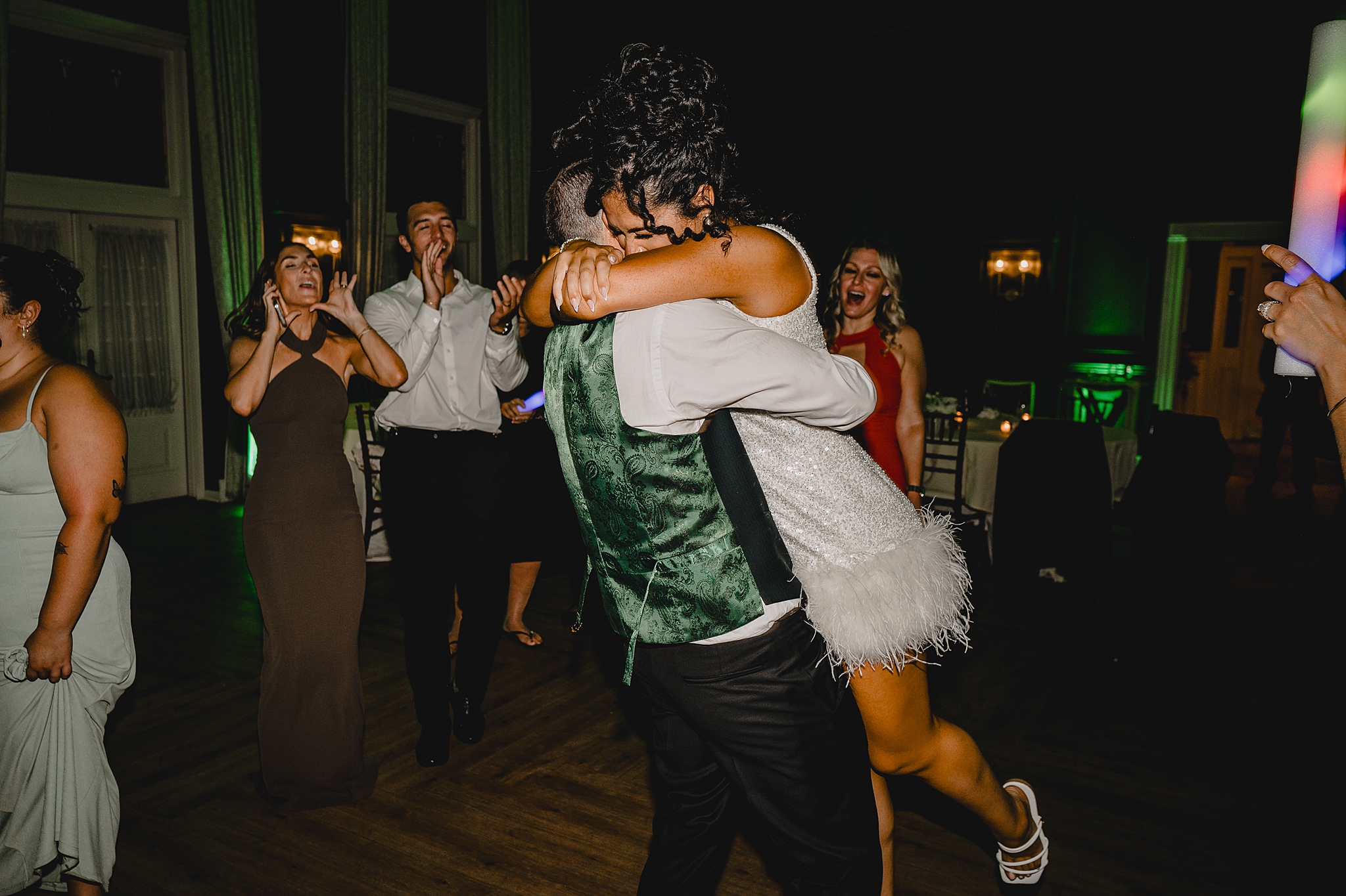 groom lifts up bride in party dress during wedding reception at David's Country Inn
