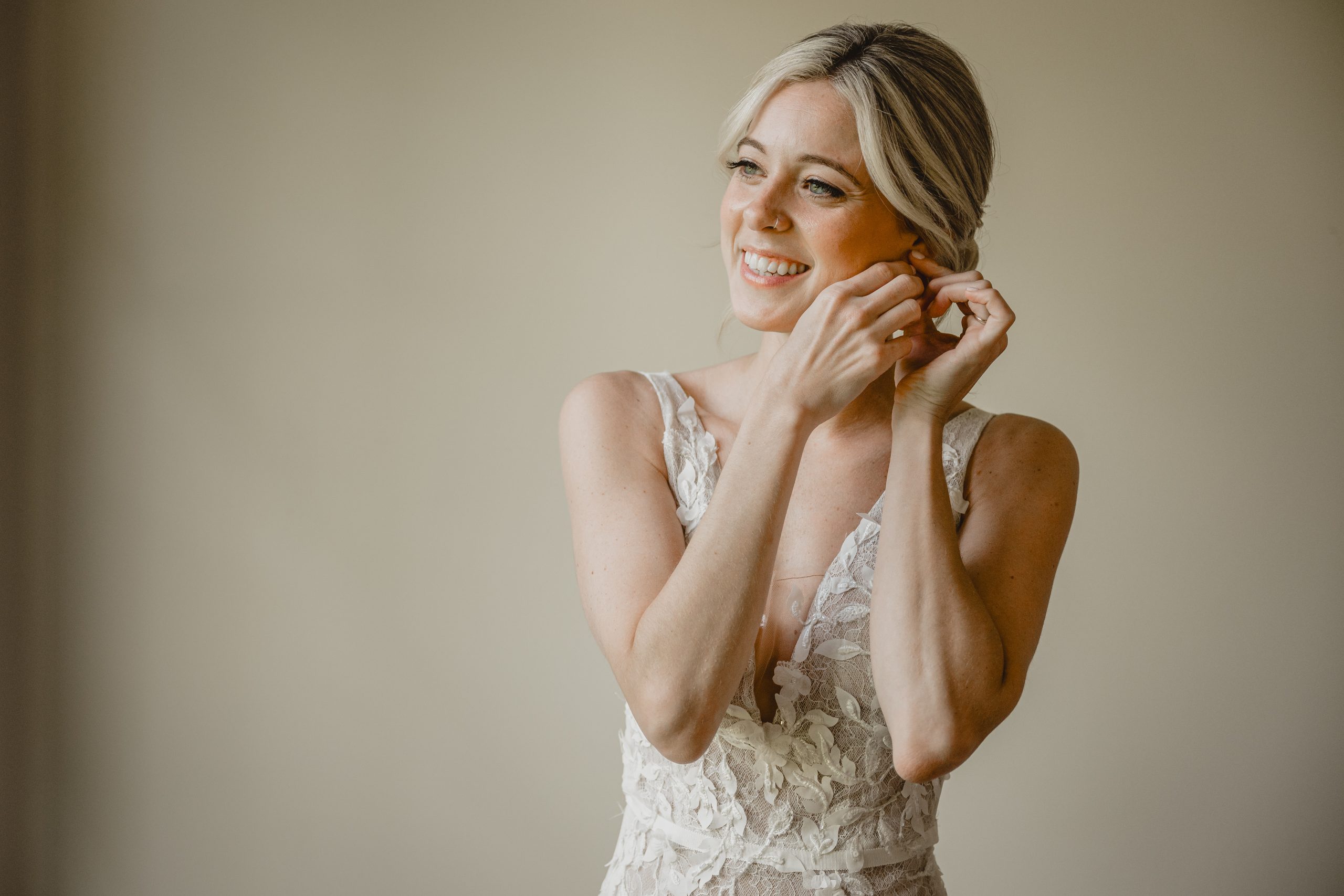 blonde bride adjusts earrings while preparing for wedding day at Perona Farms Refinery 