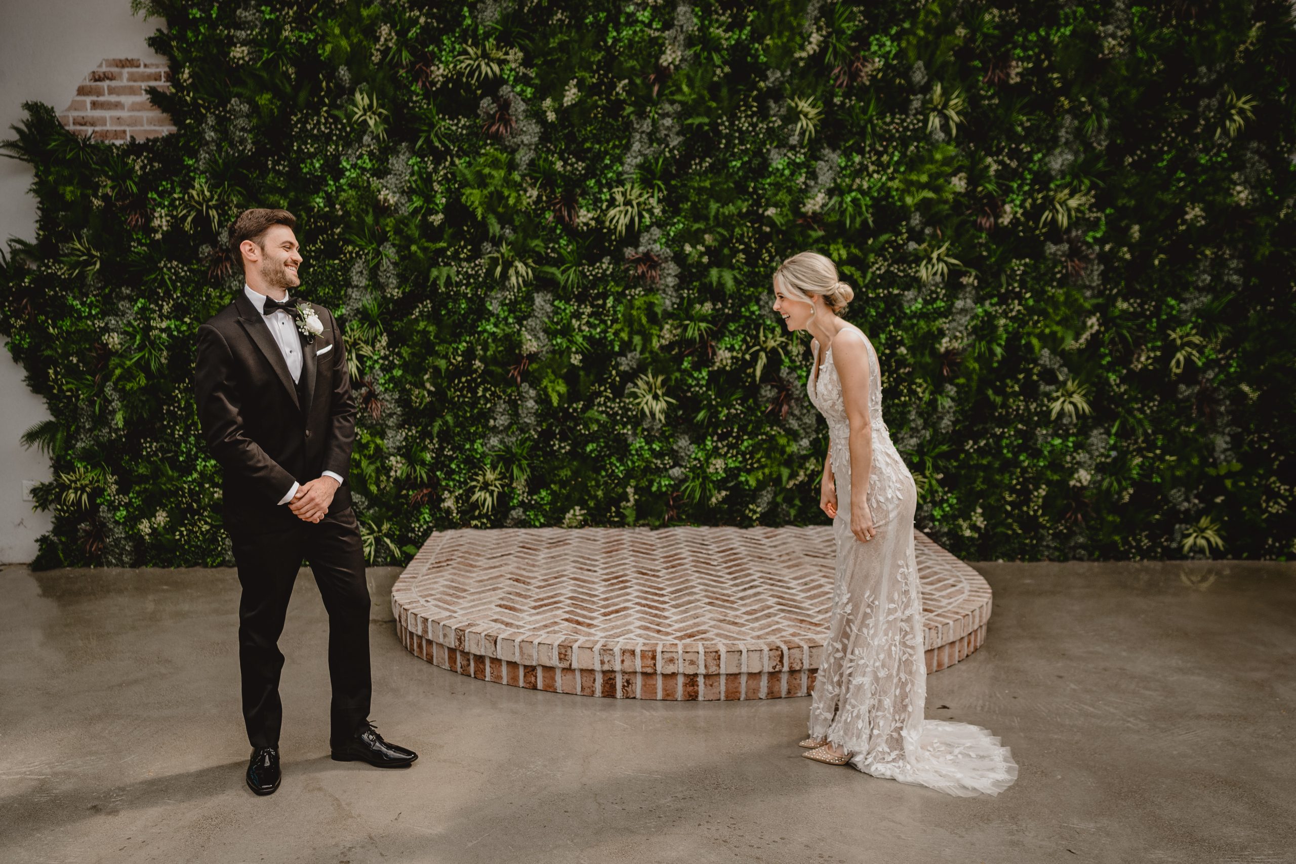 groom grins at bride during first look in courtyard at the Perona Farms Refinery