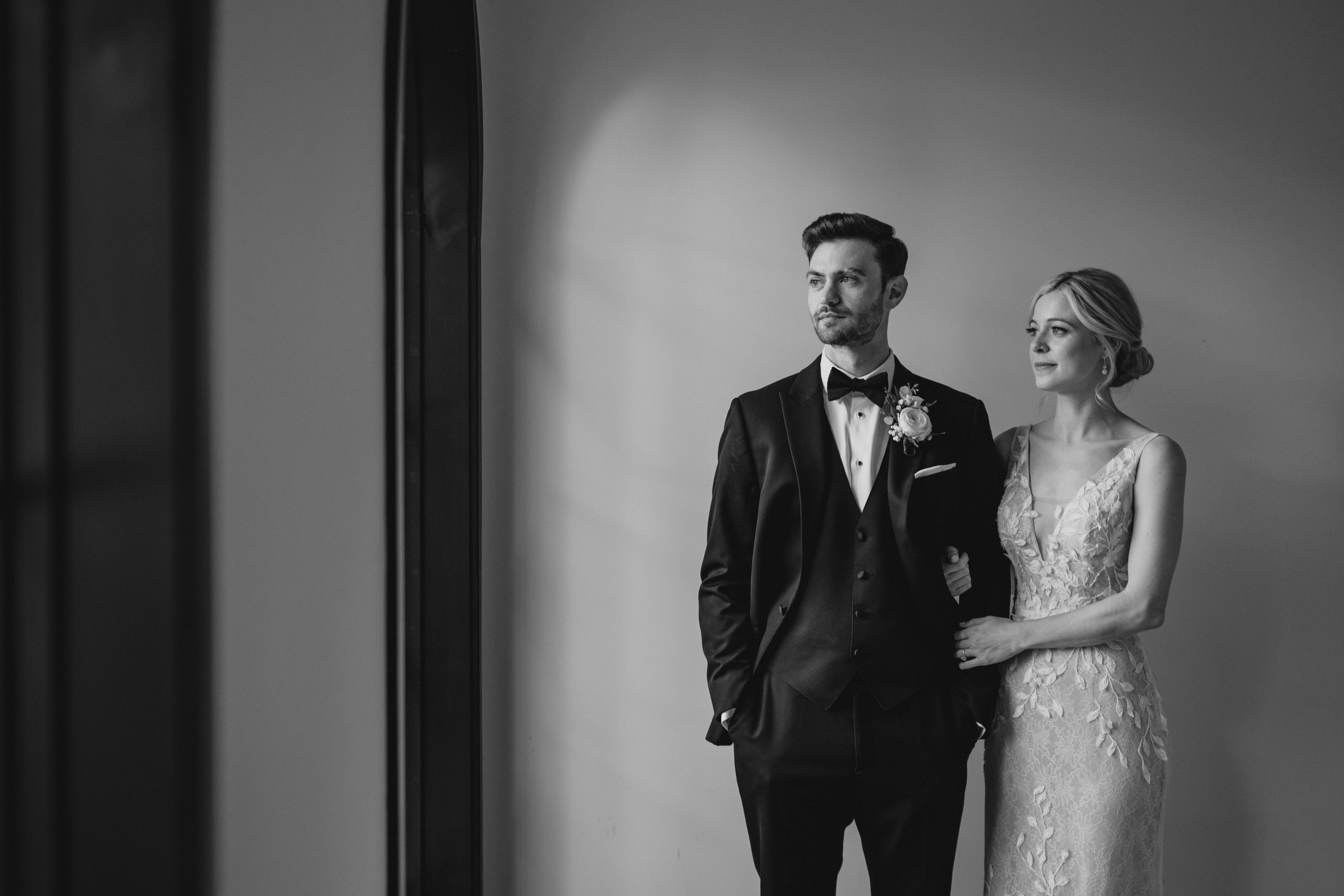 bride holds groom's arm looking out window in Andover NJ wedding venue 
