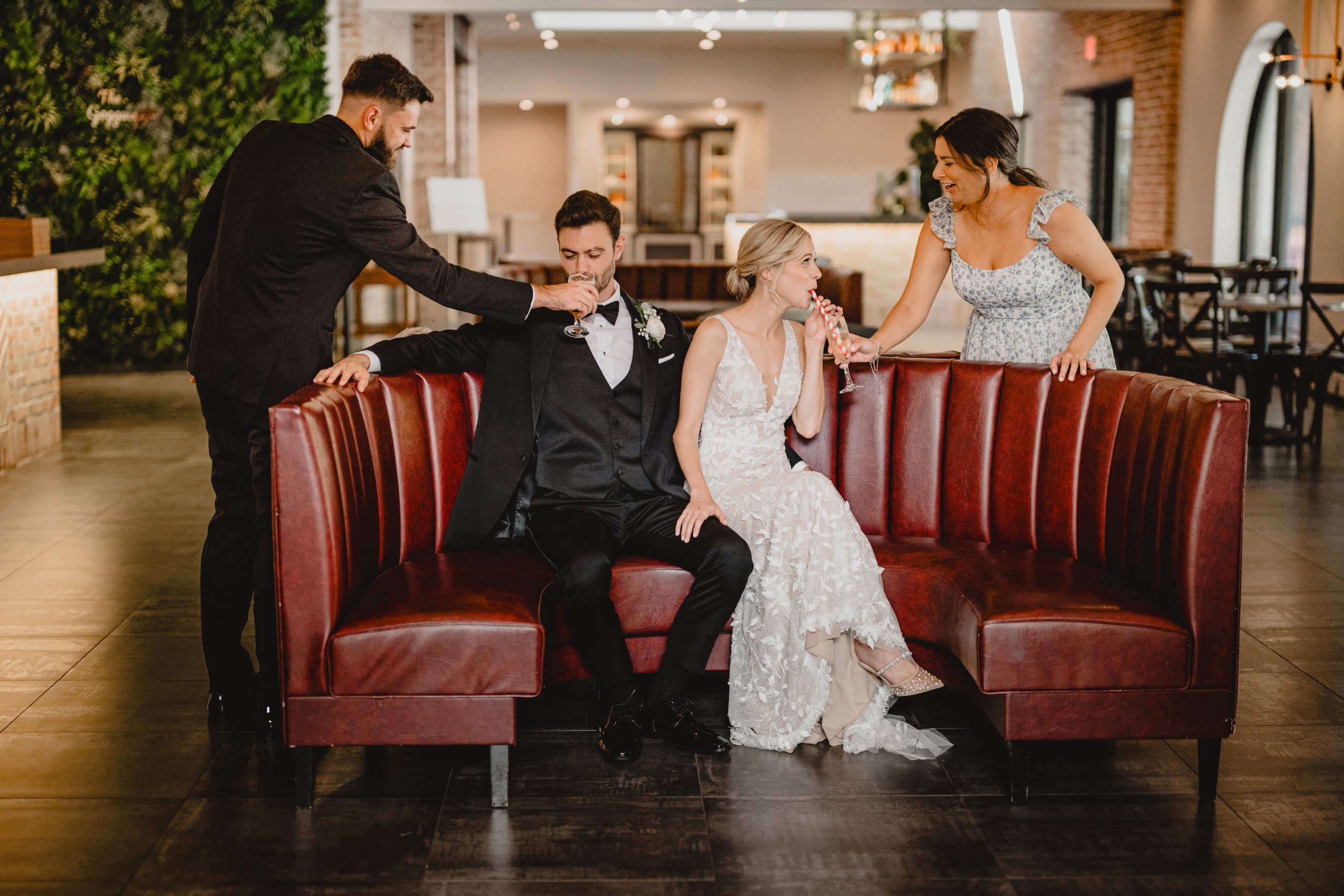 best man and maid of honor help bride and groom with drinks inside the Perona Farms Refinery