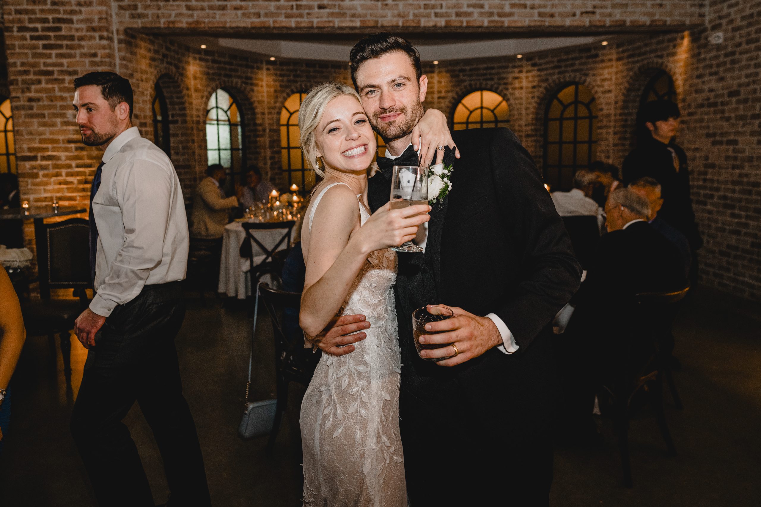 bride and groom hug holding signature cocktails during wedding reception in Andover NJ