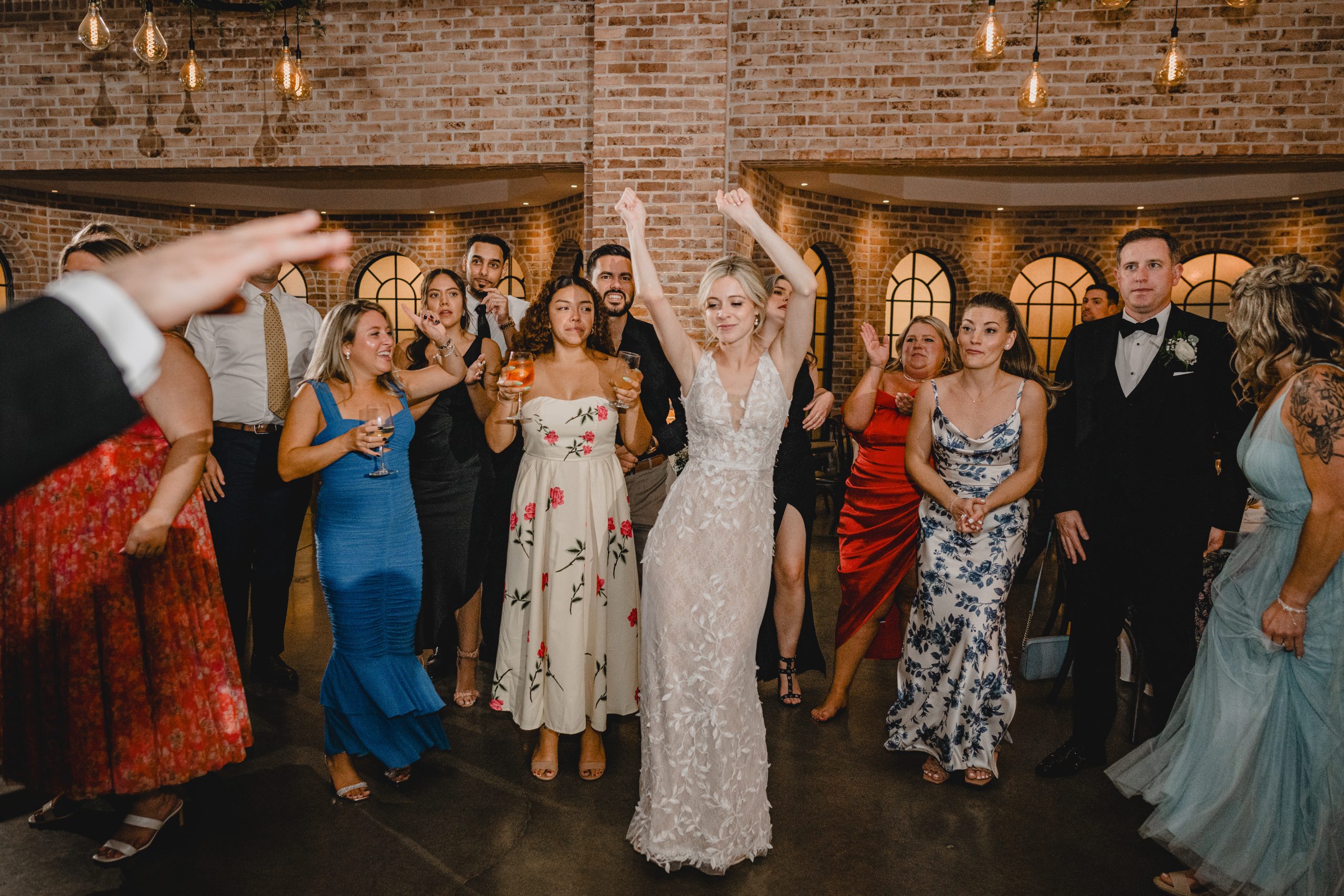 bride twirls with hands in the air while dancing with wedding guests at the Perona Farms Refinery