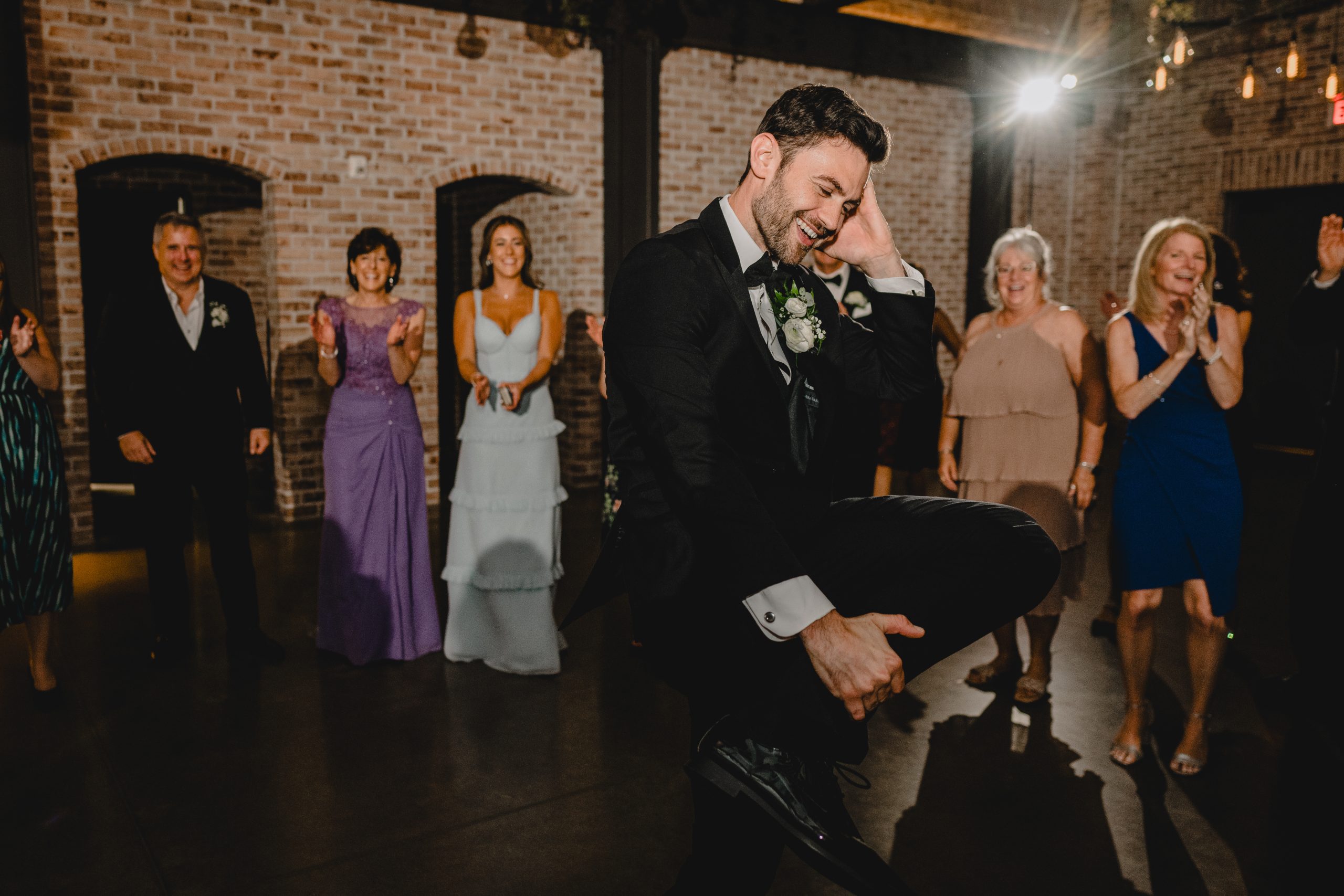groom dances with wedding guest in a circle around him at the Perona Farms Refinery