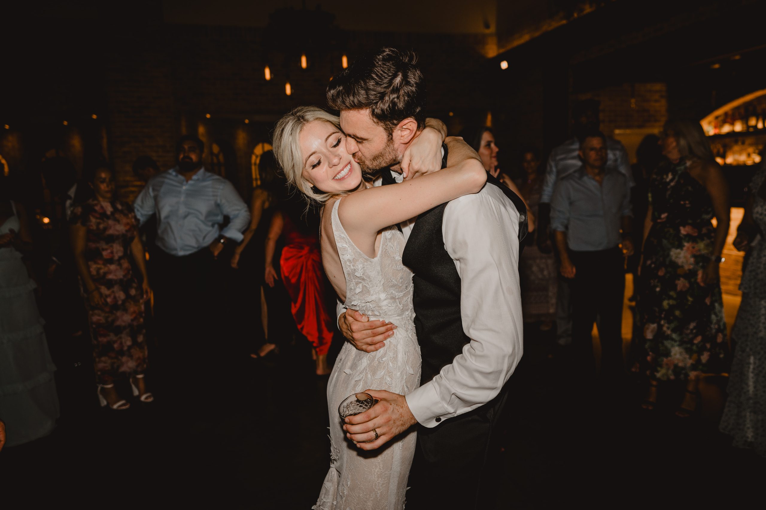groom hugs bride to him kissing her cheek during wedding reception in Andover NJ