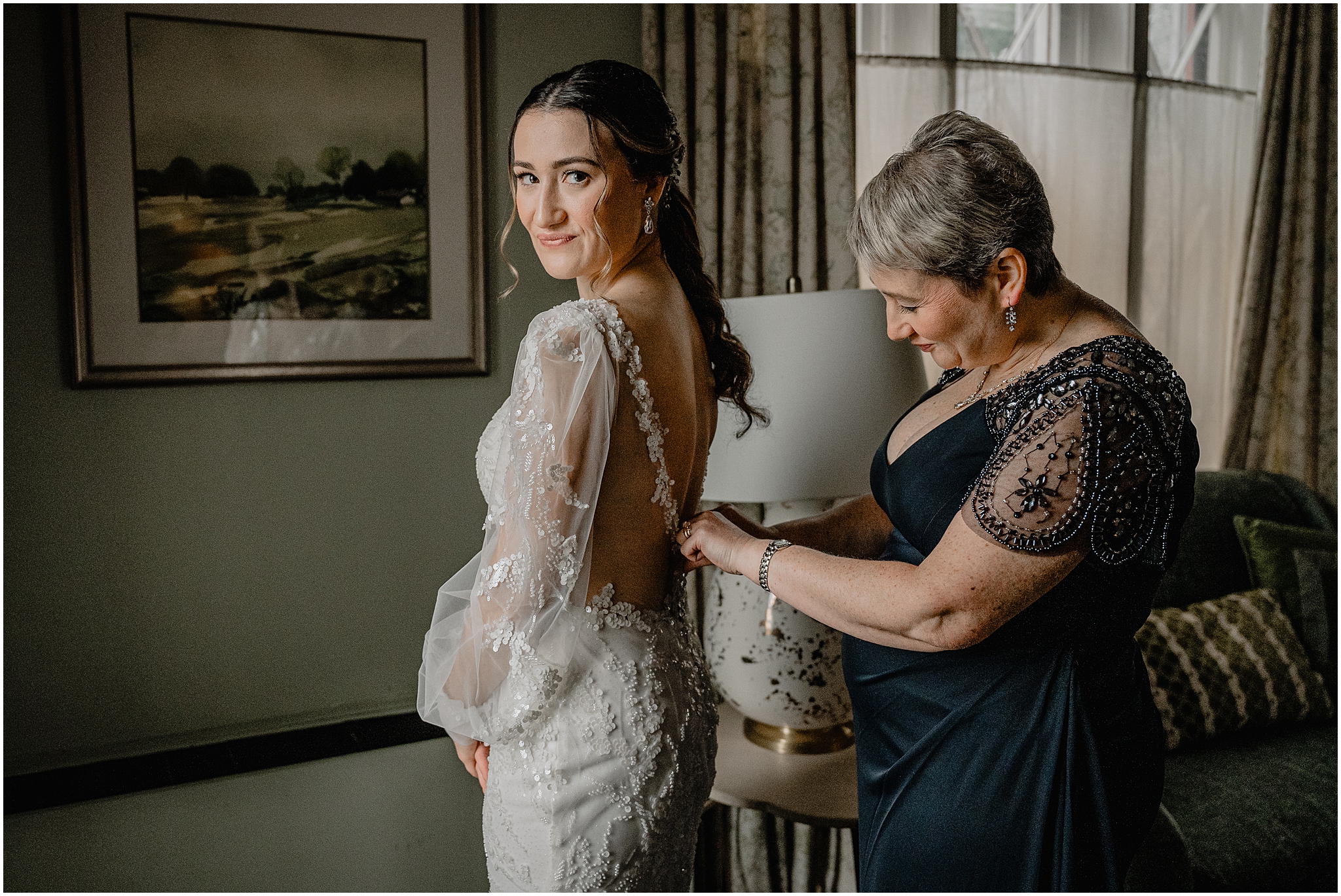mother helps button up back of wedding gown for bride in NYC hotel room