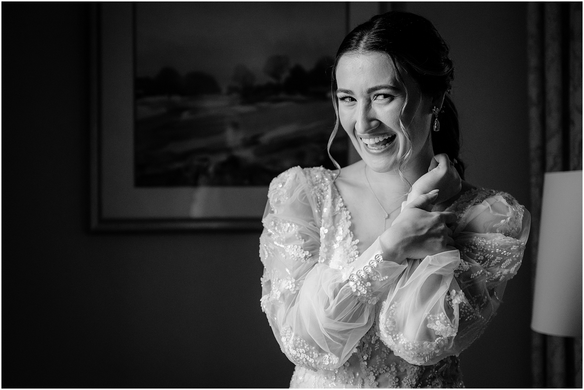 bride smiles showing off buttons on lace sleeves of wedding gown in NYC hotel