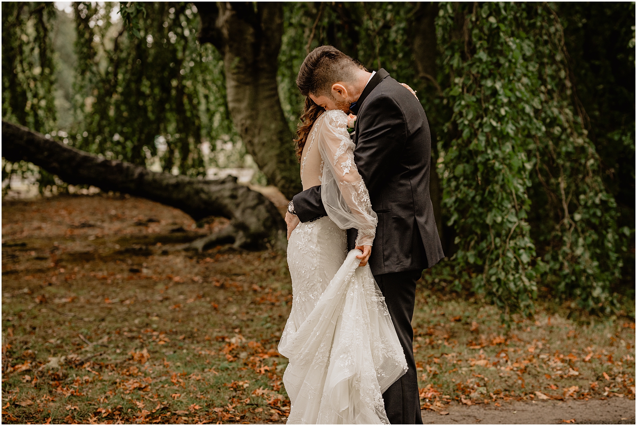 bride and groom hug tightly during first look by weeping willow