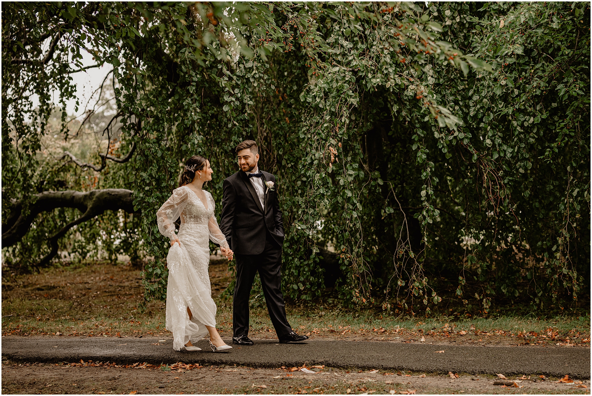 bride and groom hold hands walking down pathway outside Whitby Castle