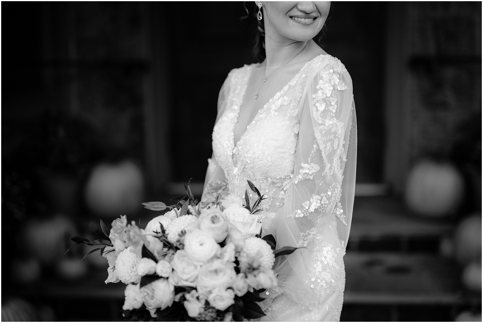 bride in sequined dress holds bouquet of white flowers during wedding day at Whitby Castle