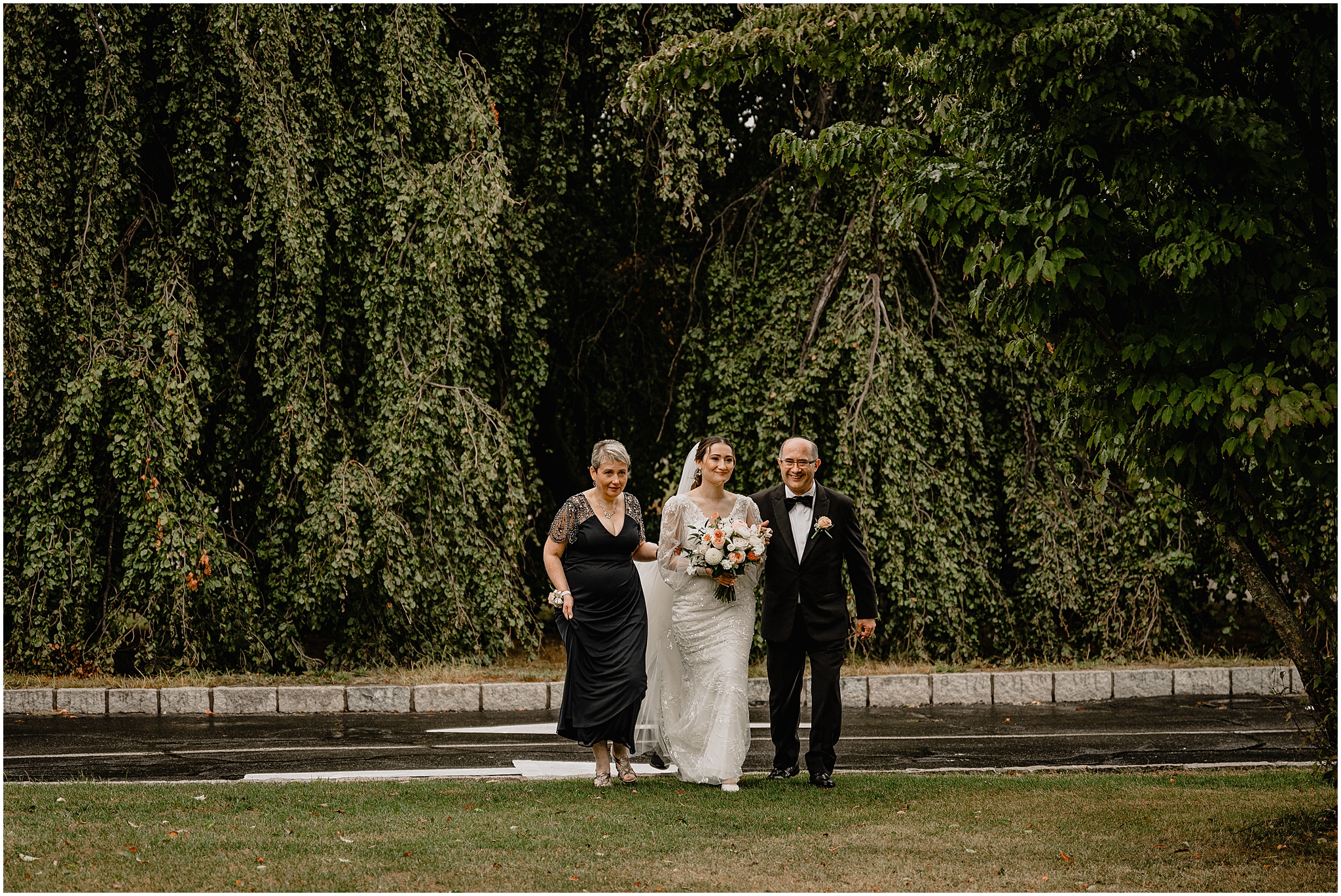 parents escort bride across lawn for wedding ceremony at Whitby Castle