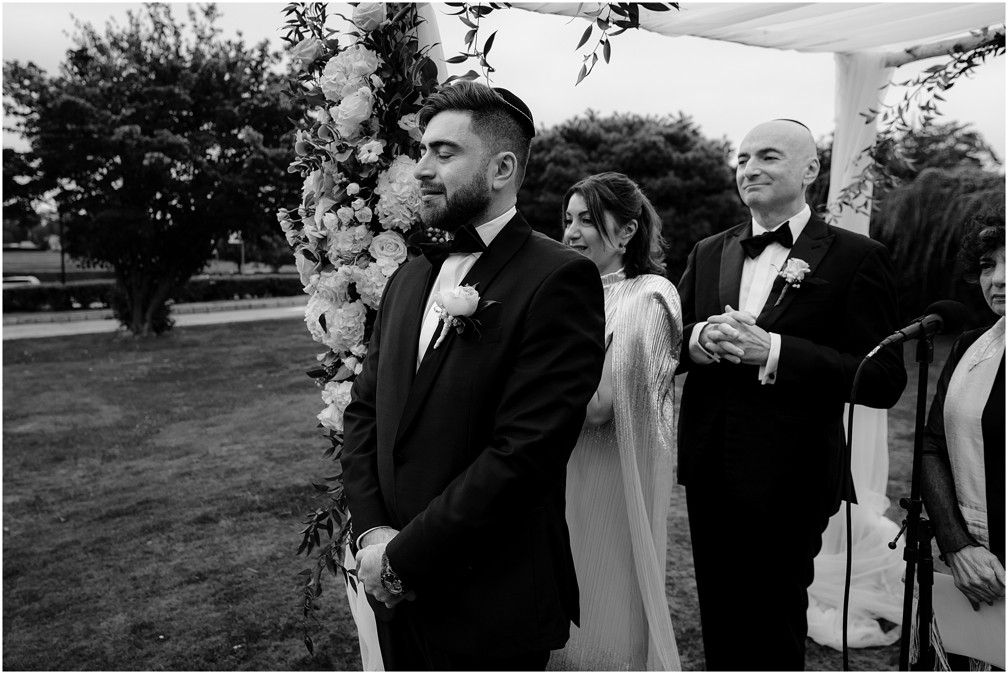 groom and parents watch bride walk down aisle with rabbi standing under chuppah at Whitby Castle
