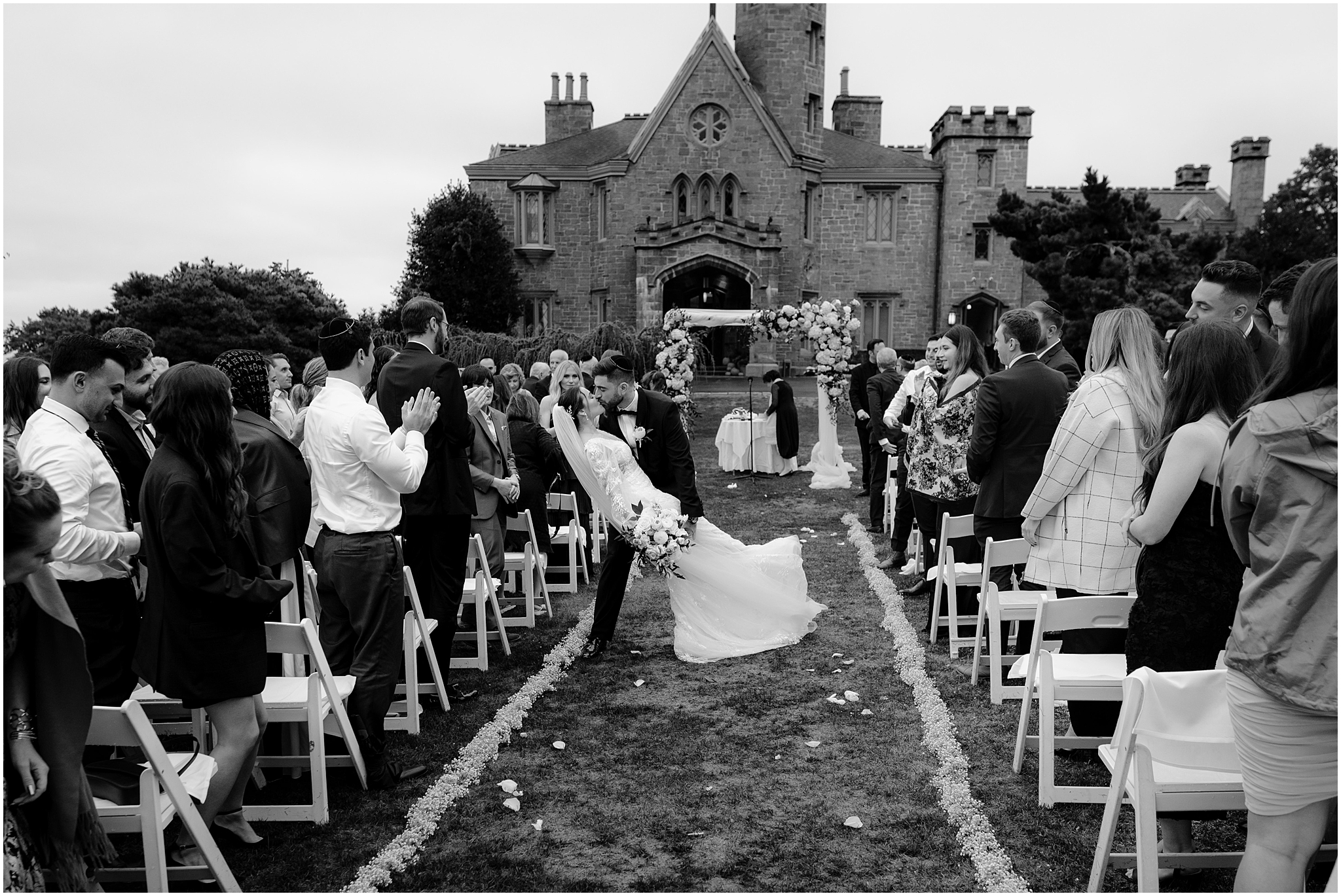 groom dips bride in aisle after wedding ceremony on the lawn of Whitby Castle