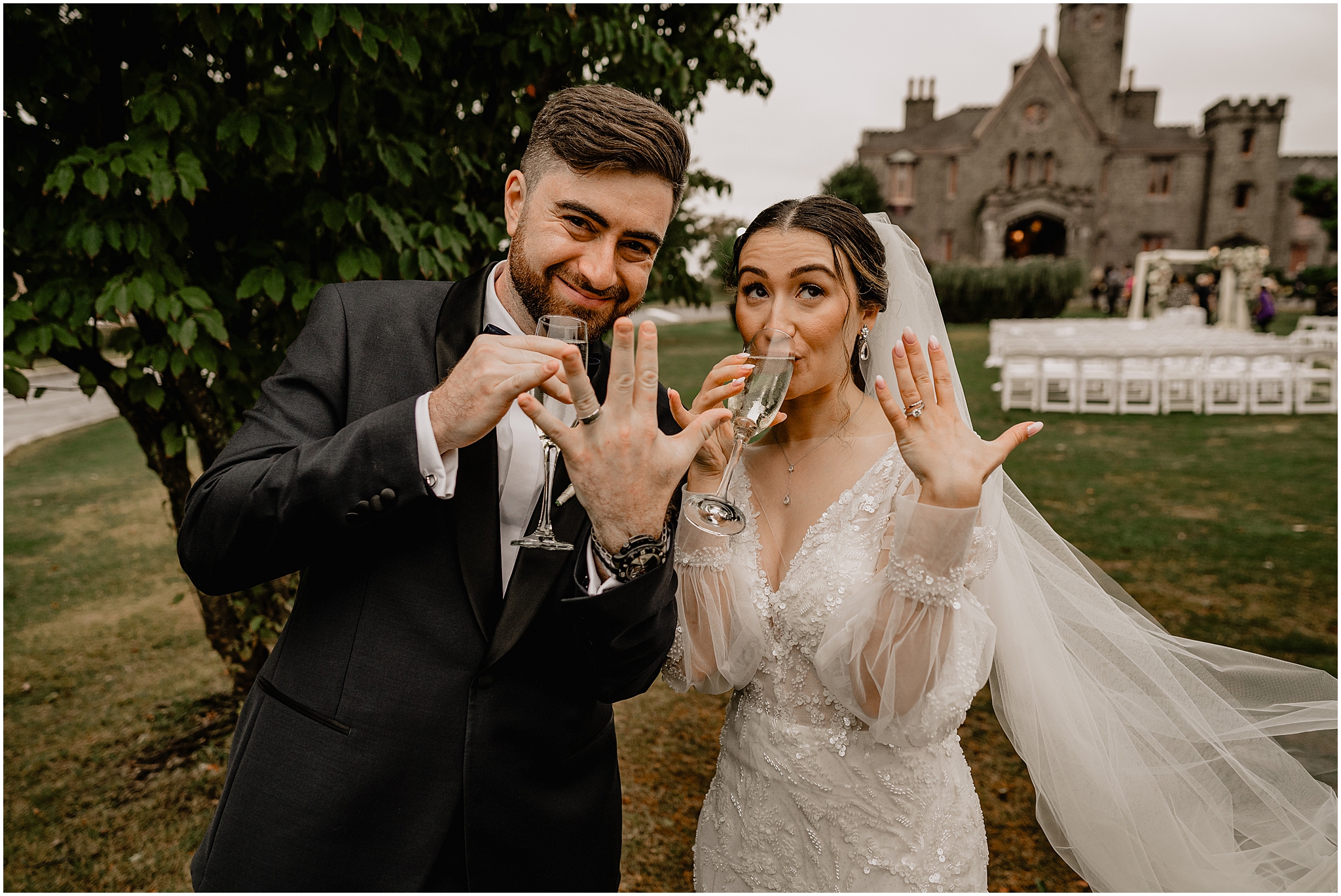 bride and groom hold glasses of champagne showing off wedding rings 