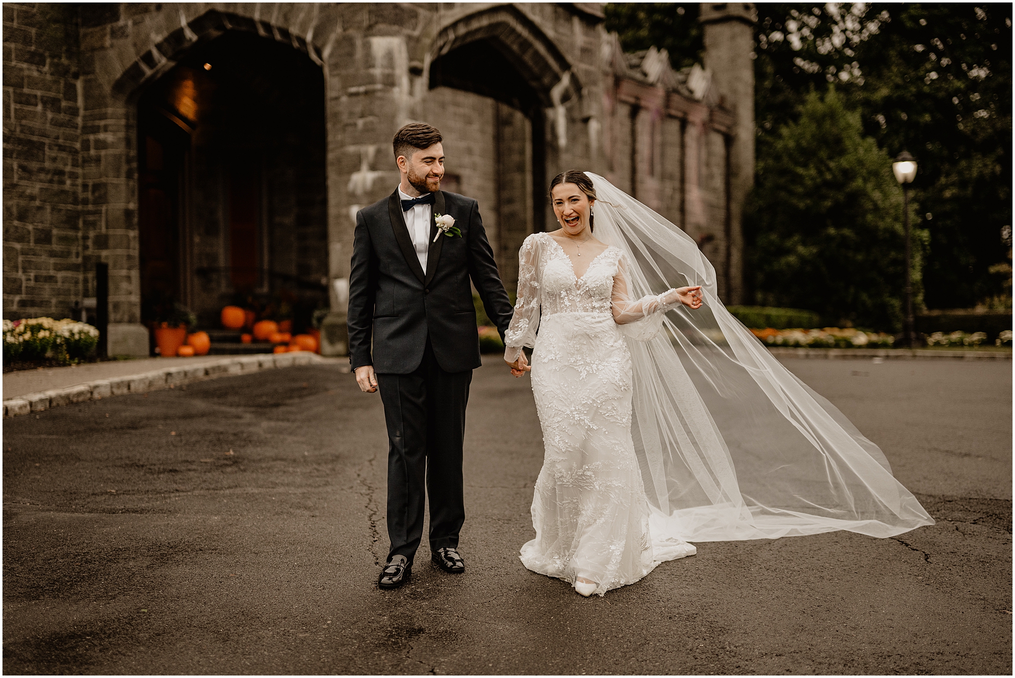 bride and groom walk outside Whitby Castle holding hands