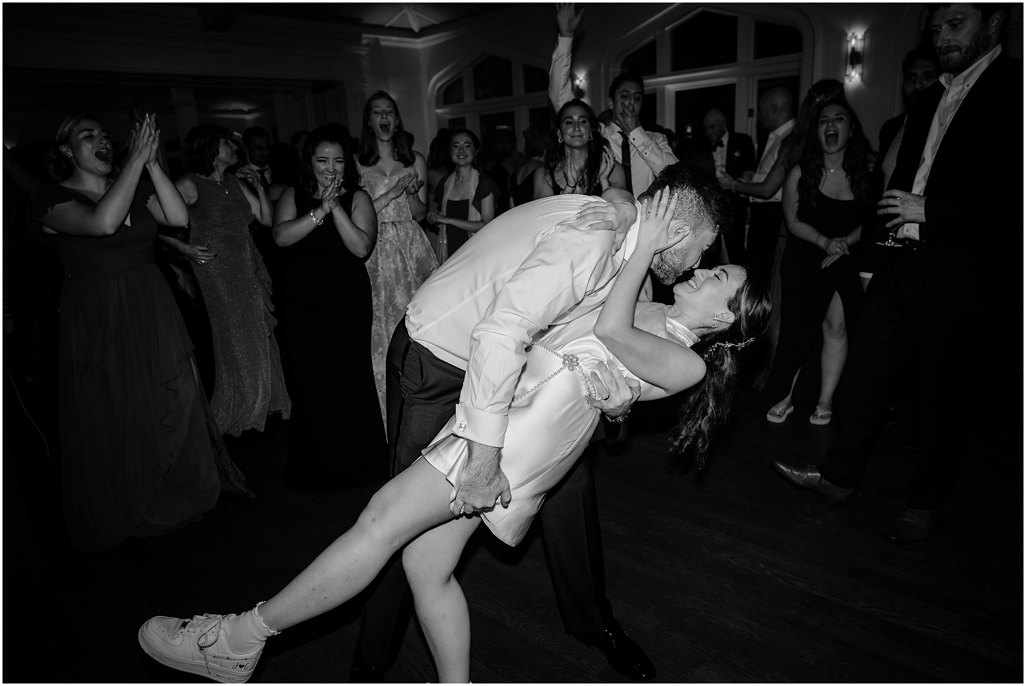 groom dips bride kissing her on dance floor in short dress and sneakers