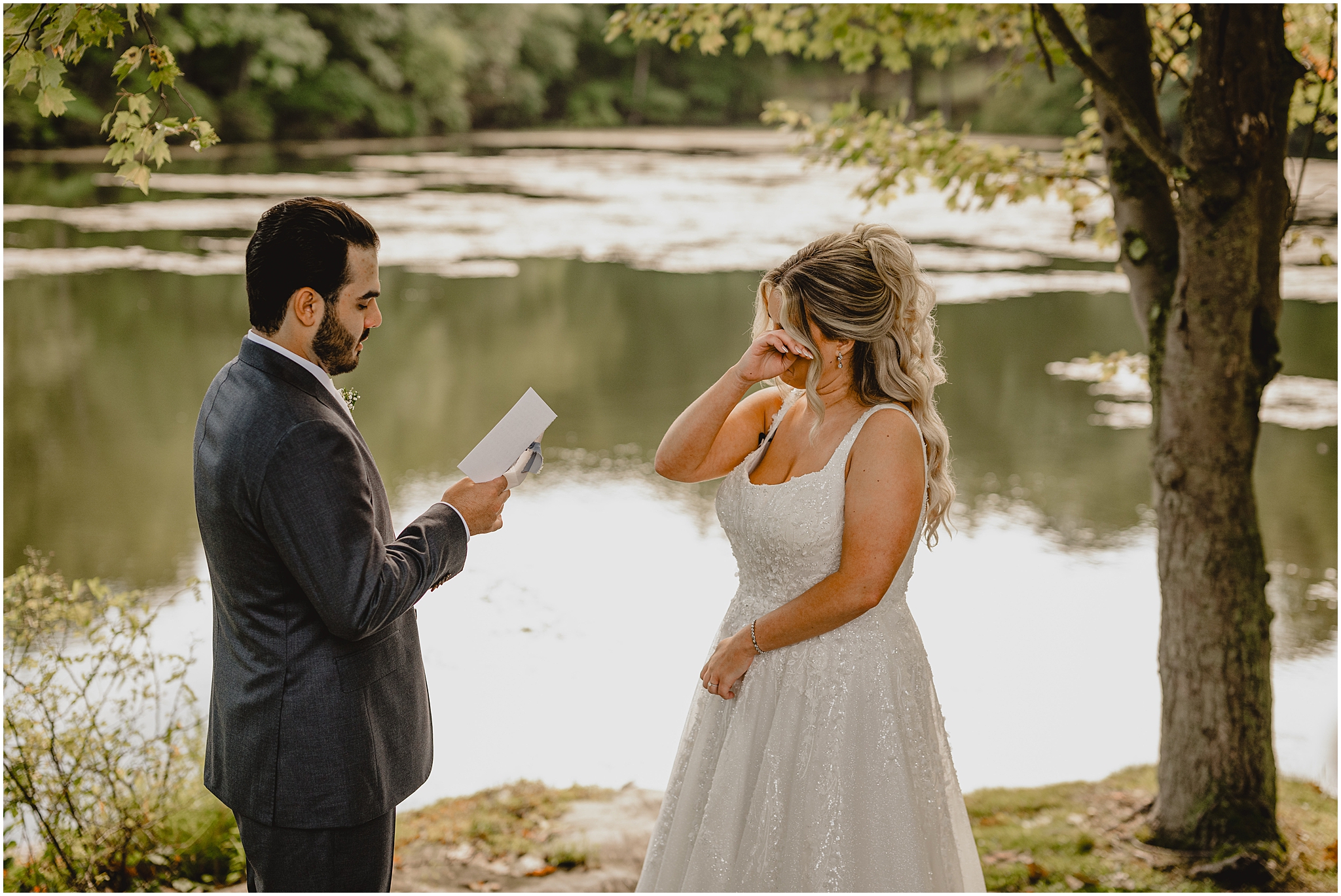 groom reads vows to bride during first look beside pond