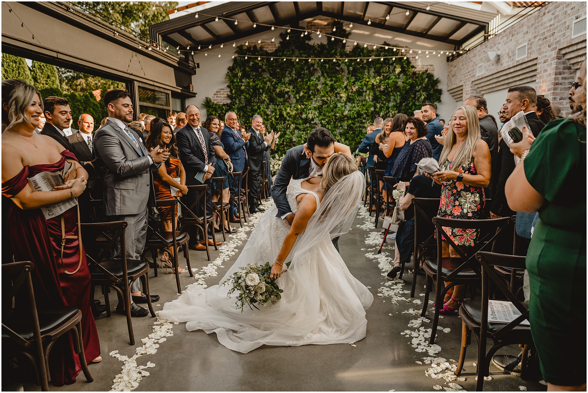 groom kisses bride in aisle of ceremony site at the Refinery at Perona Farms