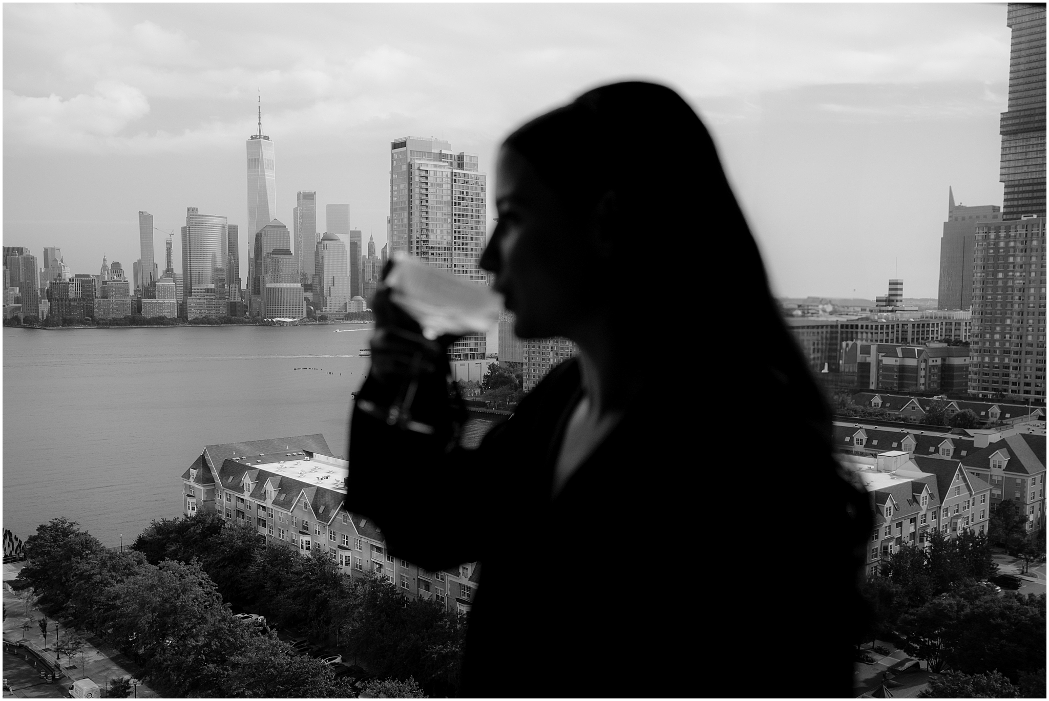 blurred photo of bride drinking champagne in front of NYC skyline on wedding day