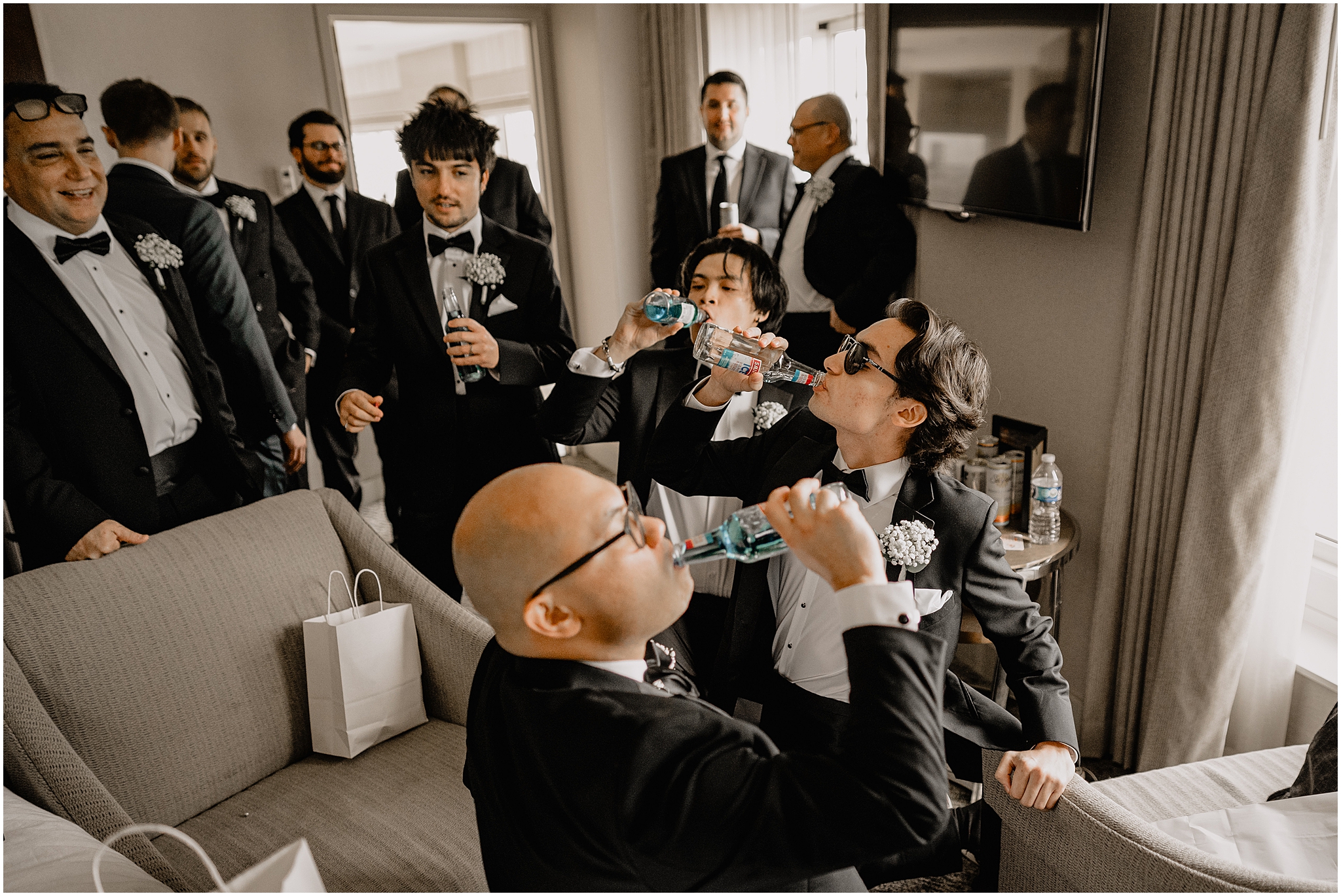 groomsmen kneel drinking Smirnoff ices in NJ hotel room