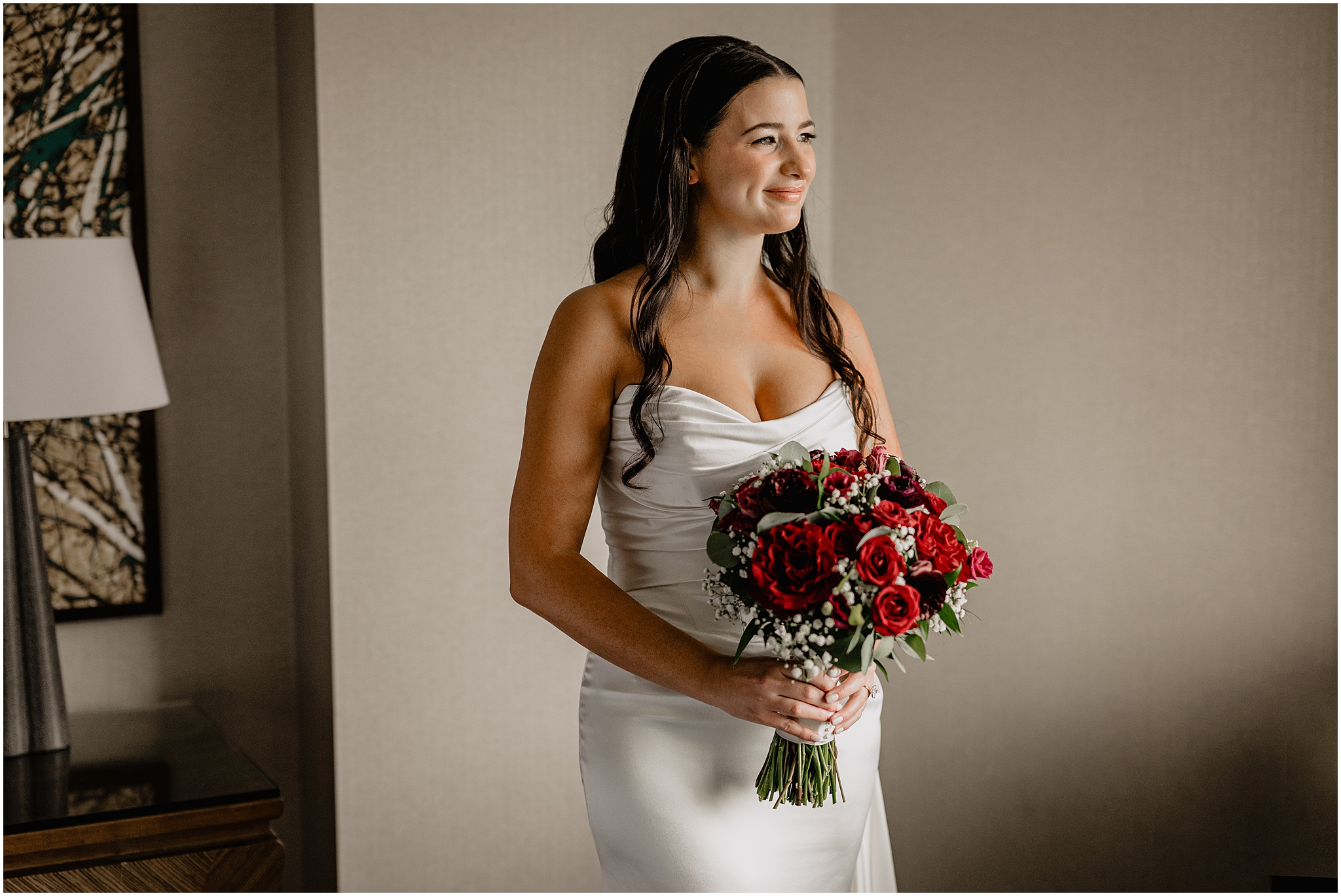 bride holds bouquet of red roses and baby's breath in New Jersey hotel room