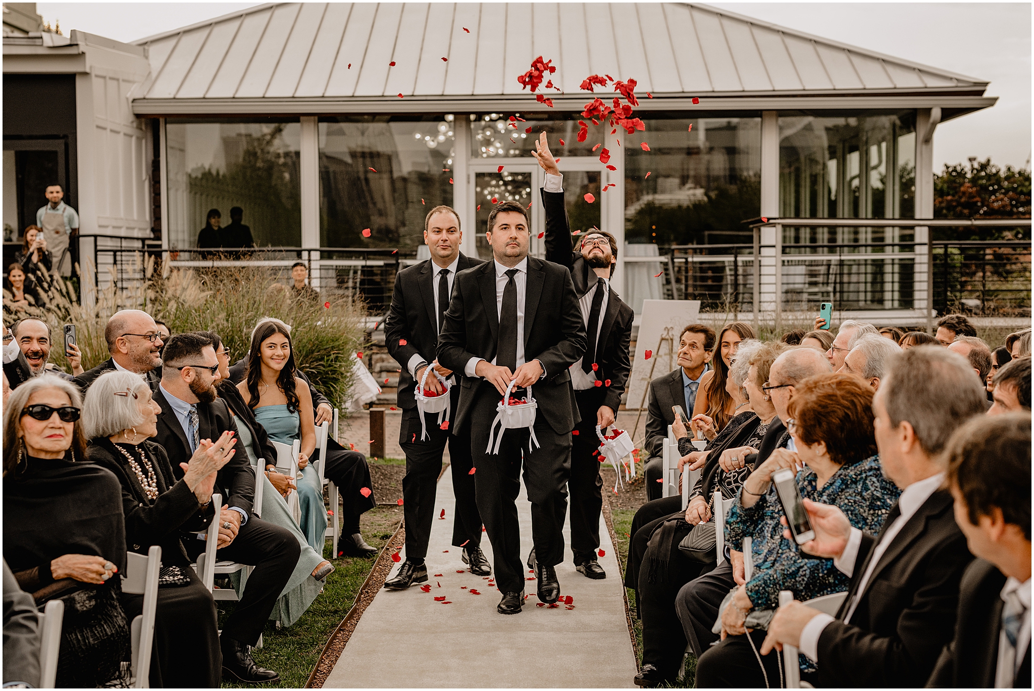 groomsmen toss red flower petals walking down the aisle at the Liberty House