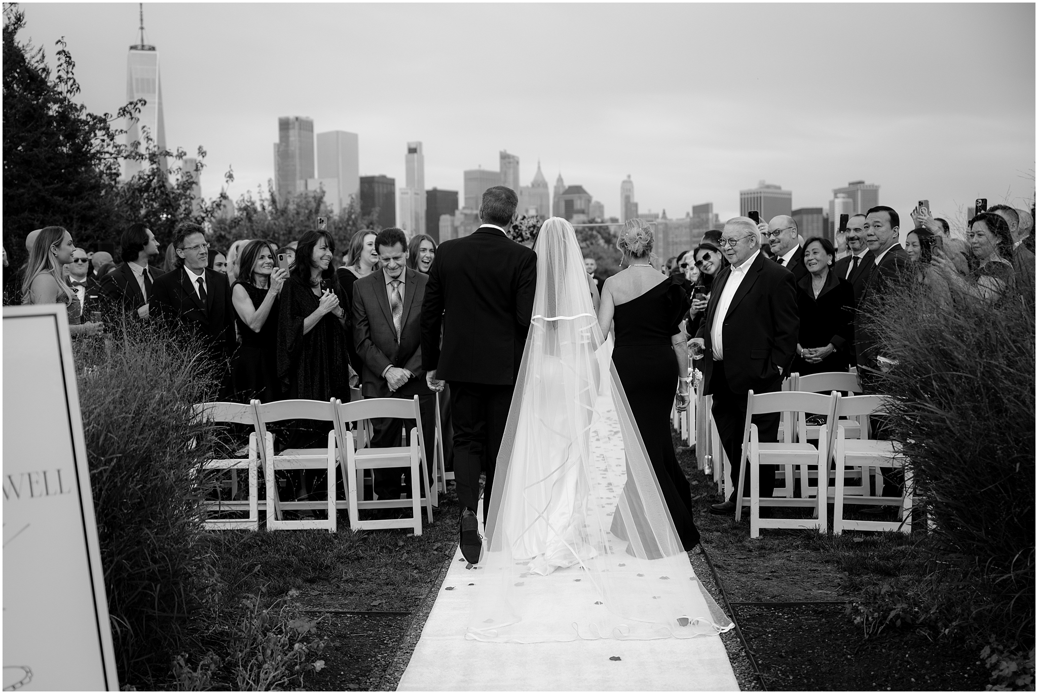 bride escorted by parents down aisle for ceremony on the lawn at the Liberty House