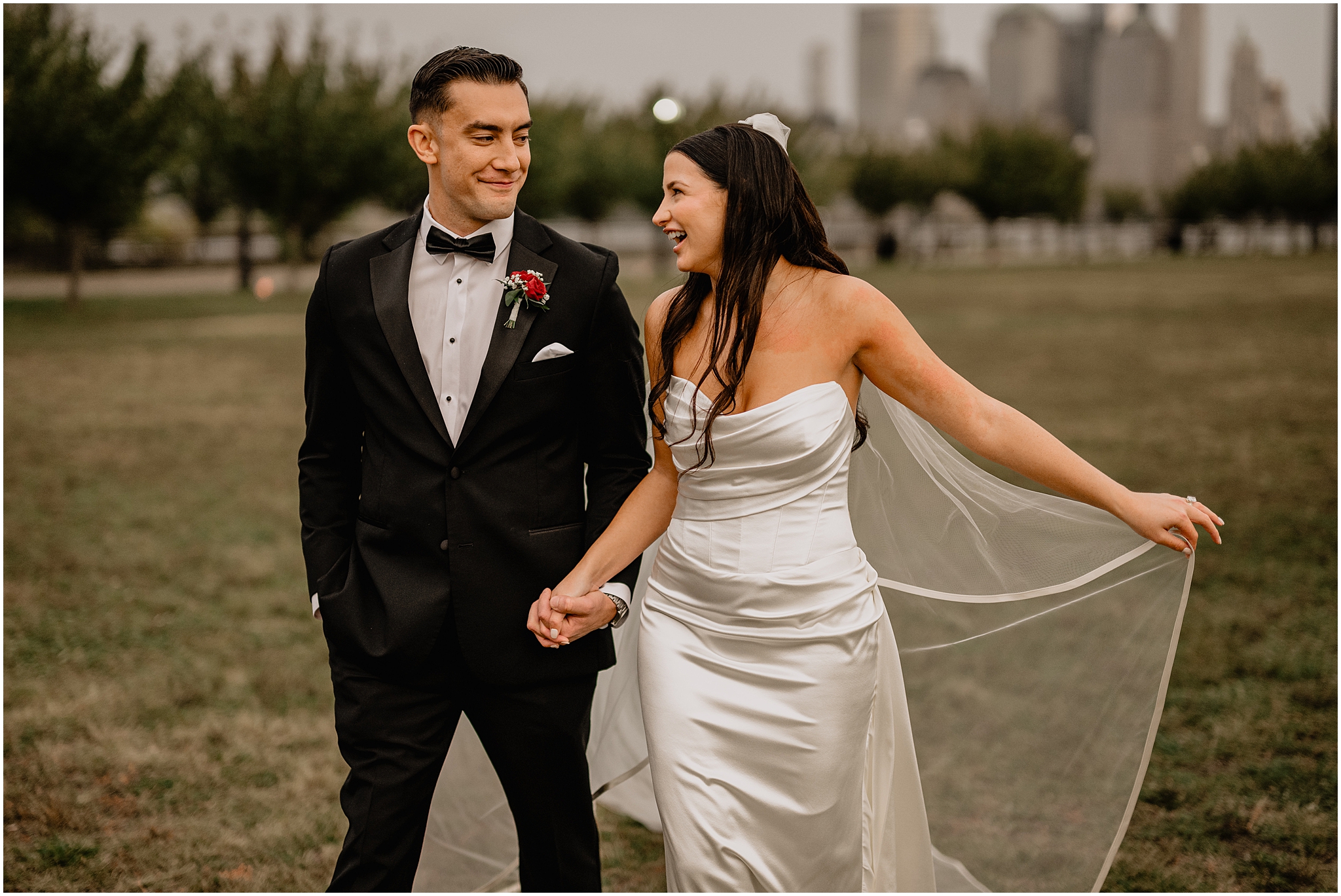 bride and groom grin at each other walking across the lawn outside the Liberty House