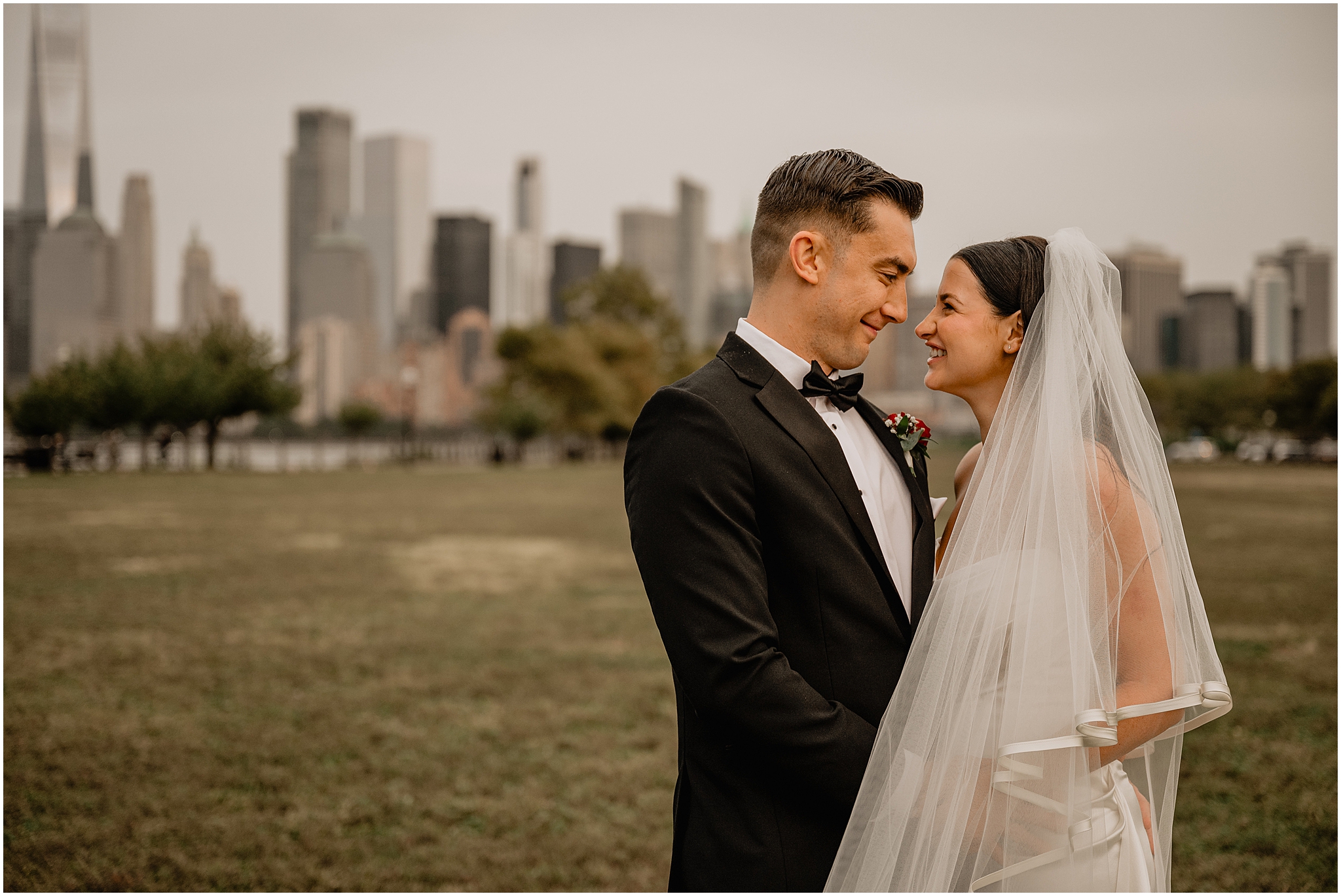 bride and groom smile at each other in front of Manhattan skyline in New Jersey 
