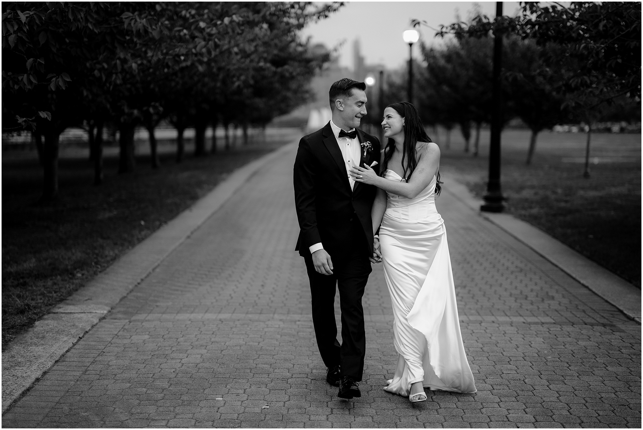 bride and groom hold hands walking on brick pathway in Jersey City 