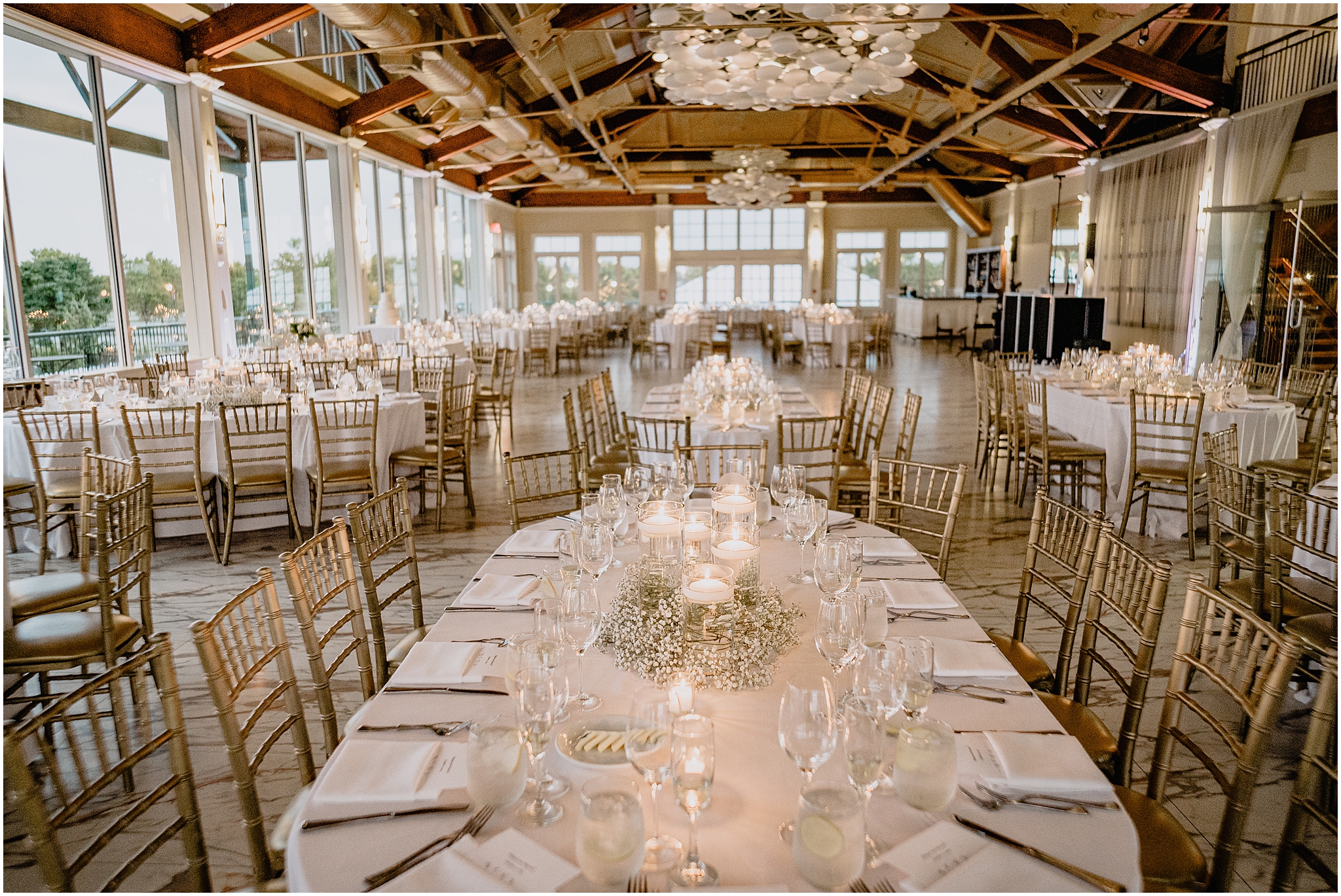 wedding reception setup at the Liberty House with gold chivari chairs and candle centerpieces surrounded by baby's breath