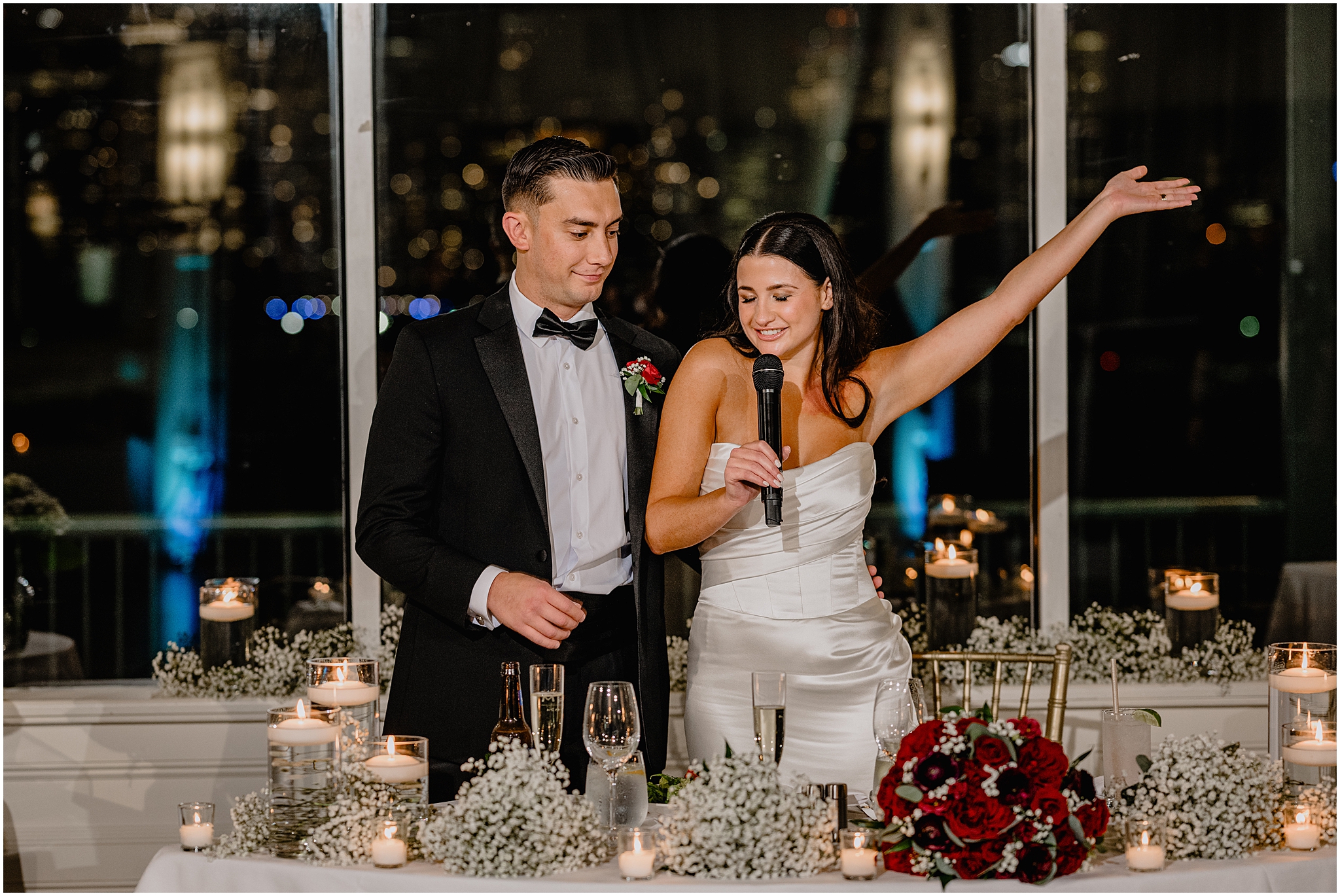 bride and groom give toast standing at sweetheart table covered in baby's breath during Jersey City wedding reception
