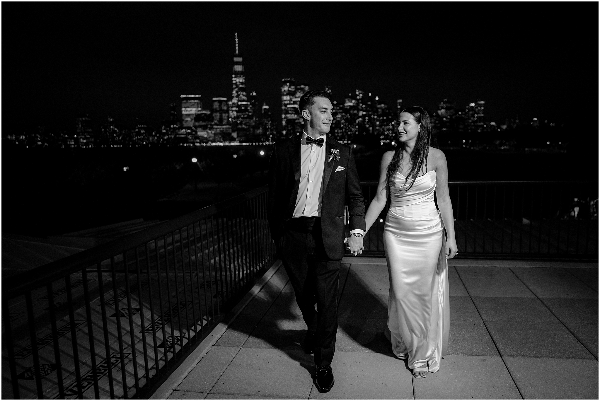 bride and groom hold hands walking on balcony of the Liberty House at night